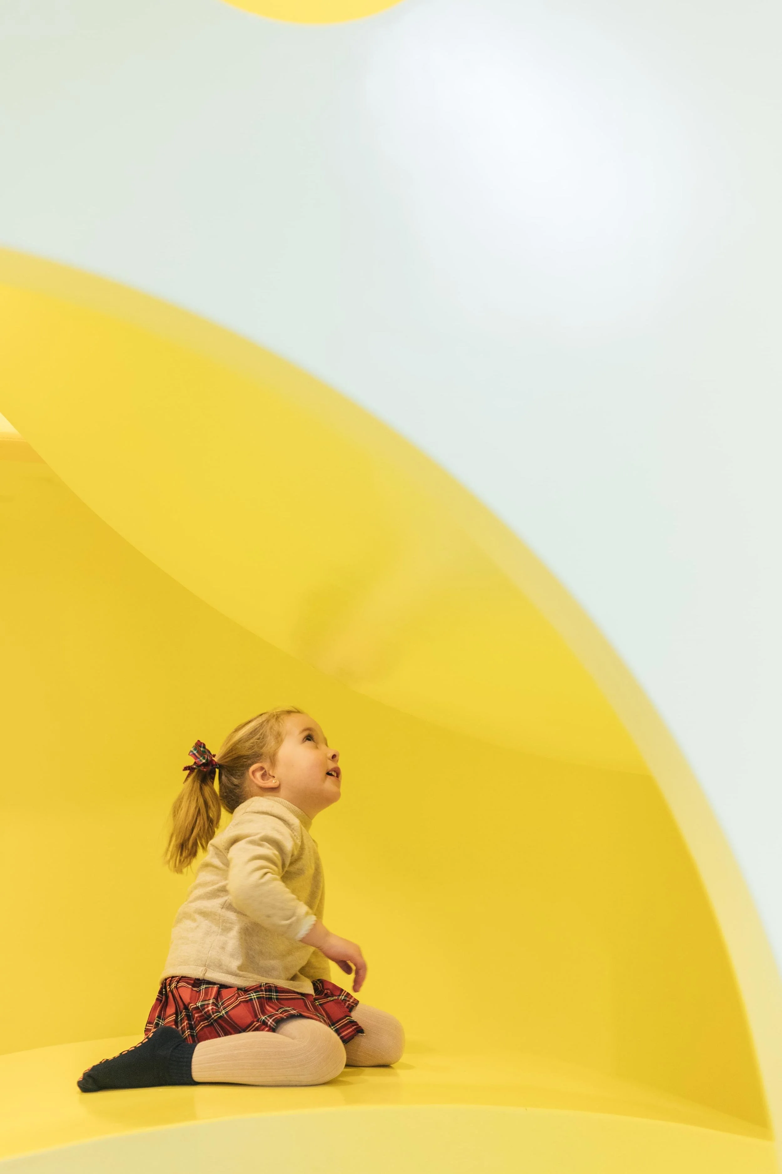 Niña sentada en el suelo de colores de Columpio Playground, espacio de juego libre para niños de 3 a 6 años en Chamartín, Madrid.