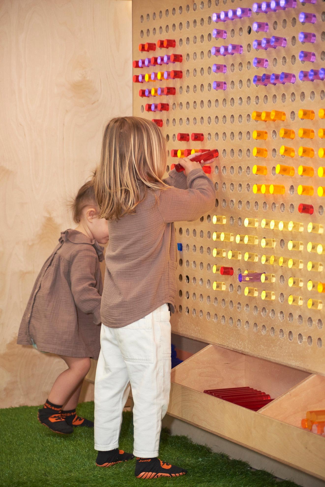 Dos niños jugando con un tablero sensorial de madera en Columpio Playground, espacio infantil en Chamartín para juego libre y actividades familiares.