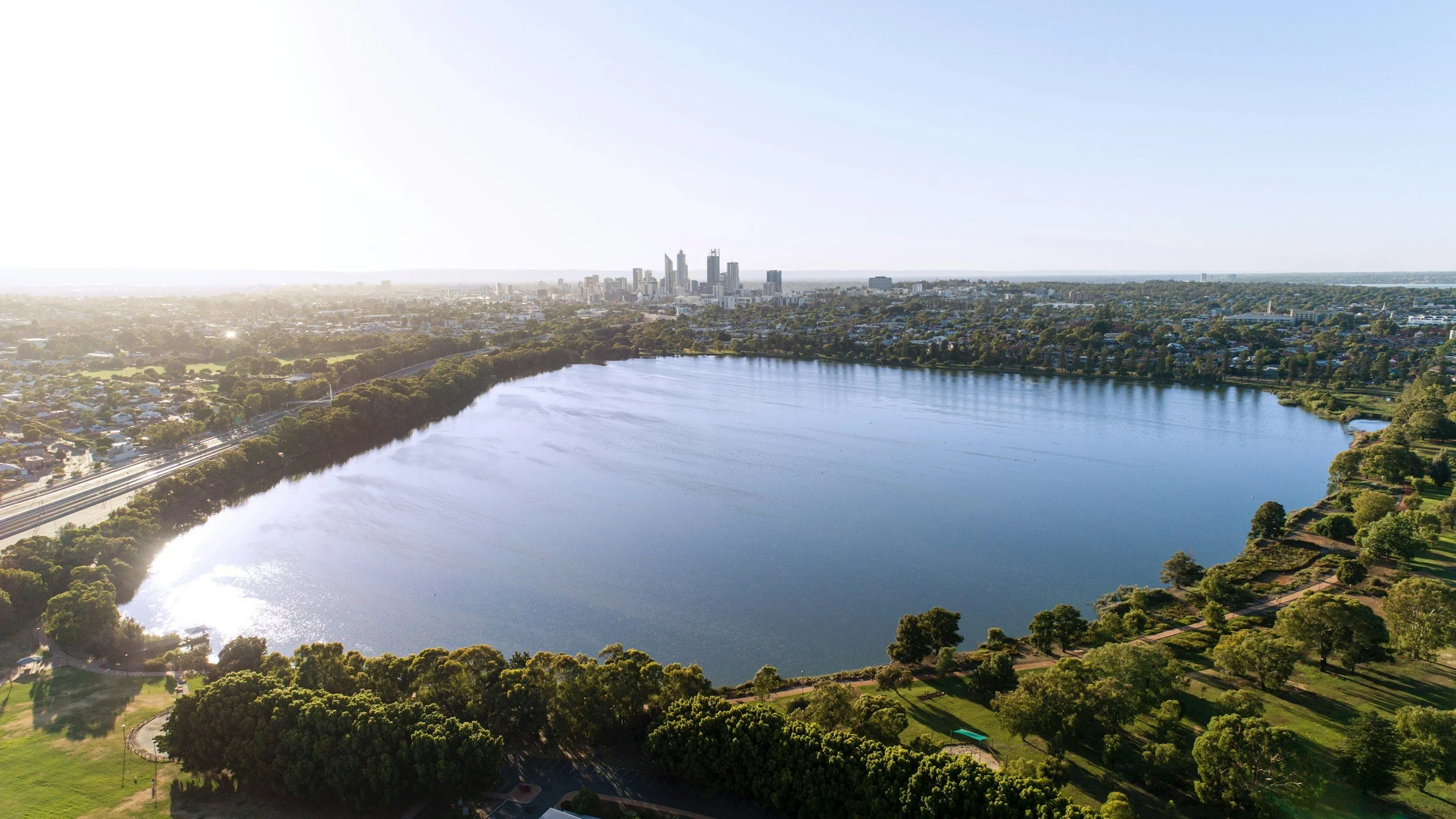 Aerial view of a river winding past the Perth city skyline