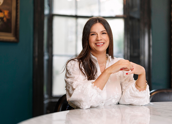 Aoife sitting in front of a table facing the camera smiling
