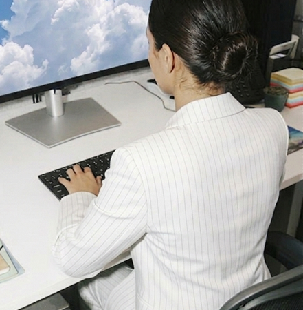 a person in corporate attire working in front of a computer desk