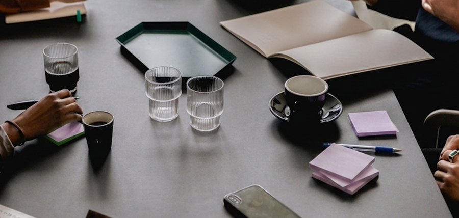 a corporate workshop table with a notebook, sticky notes, a phone, and beverages