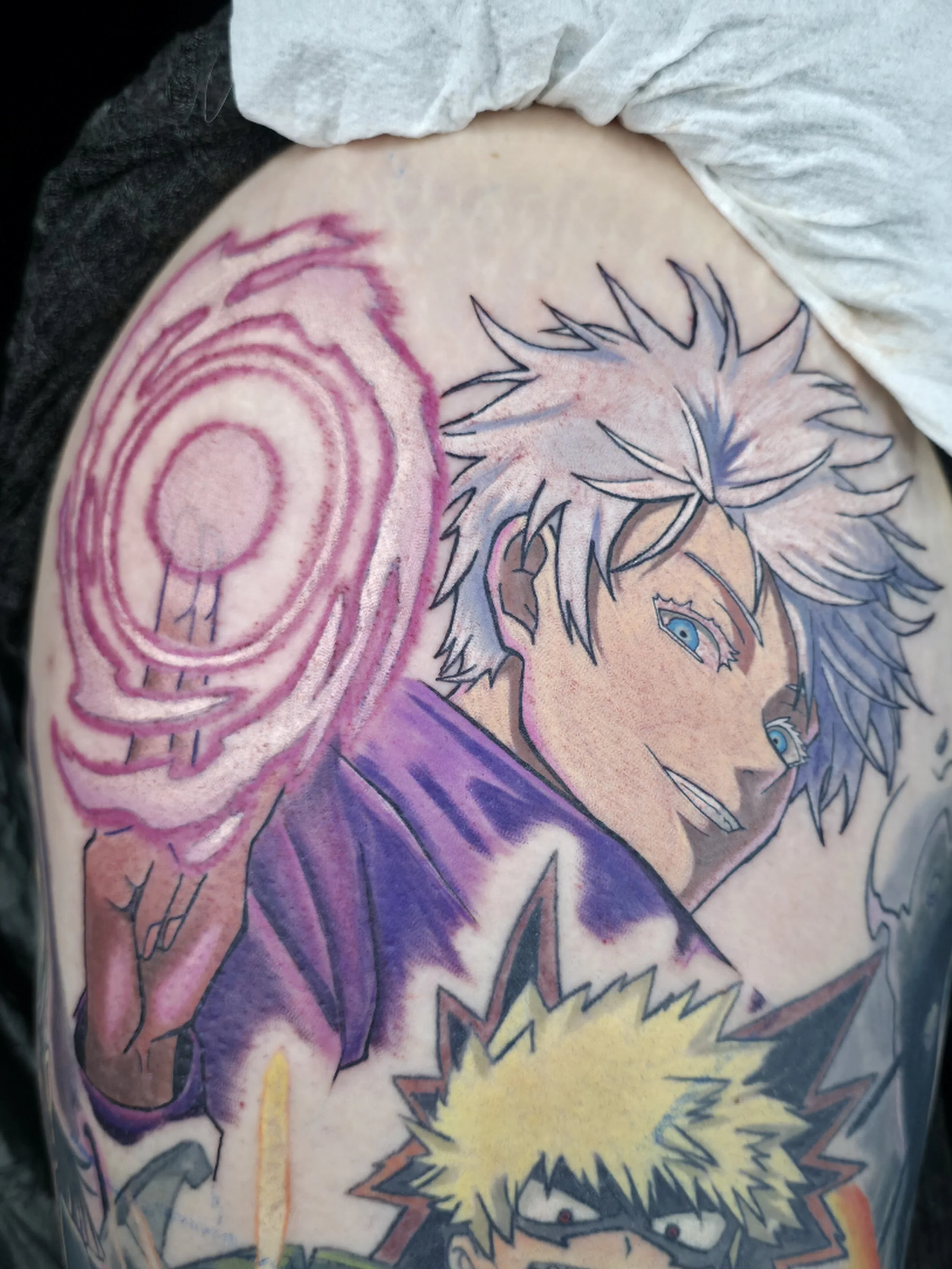 Tattoo of a manga-style character with spiky hair and intense expression, surrounded by vibrant colors like purple, yellow, and orange.