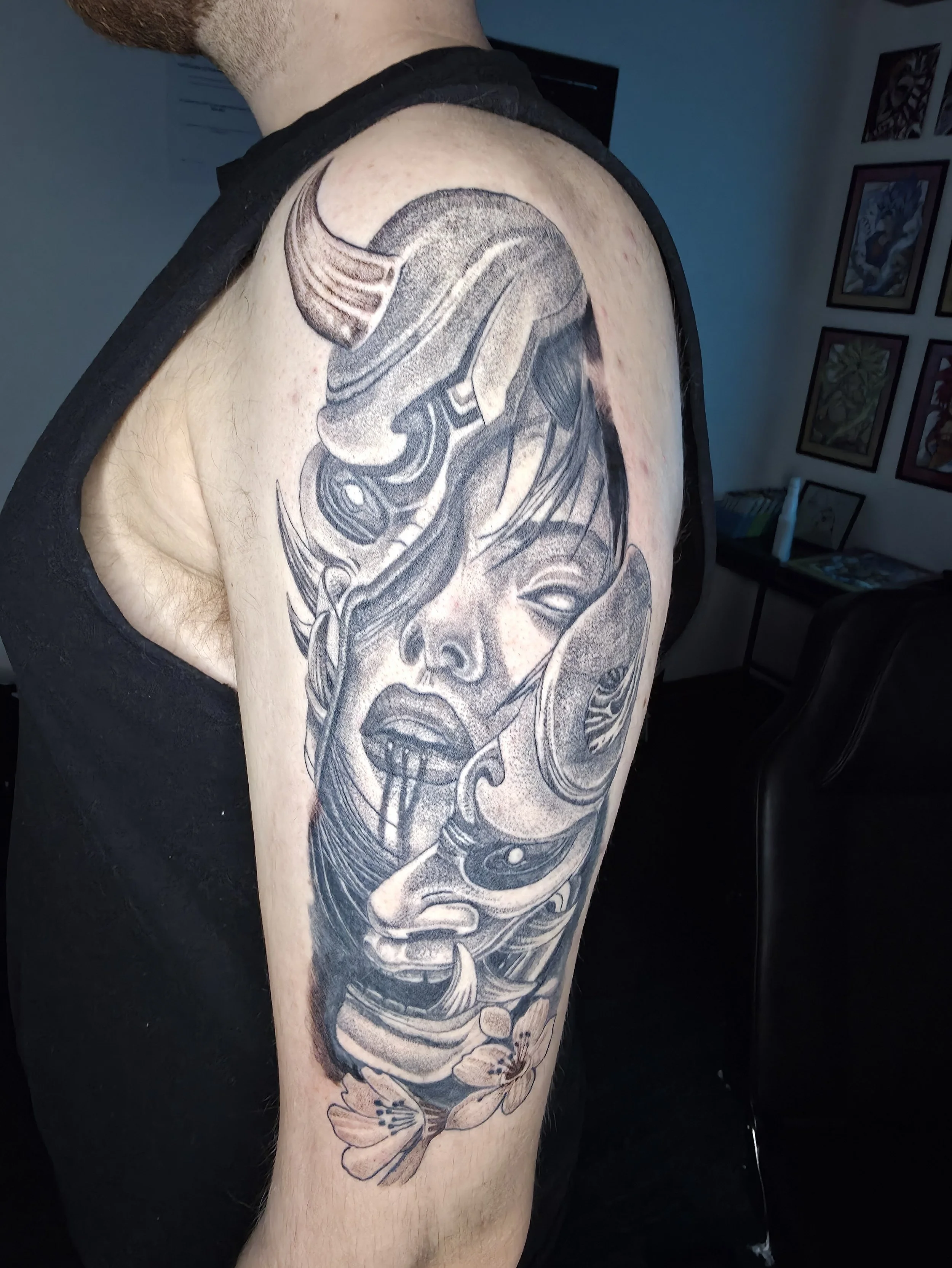 Tattoo of a woman's face with flowers on the shoulder and upper arm.