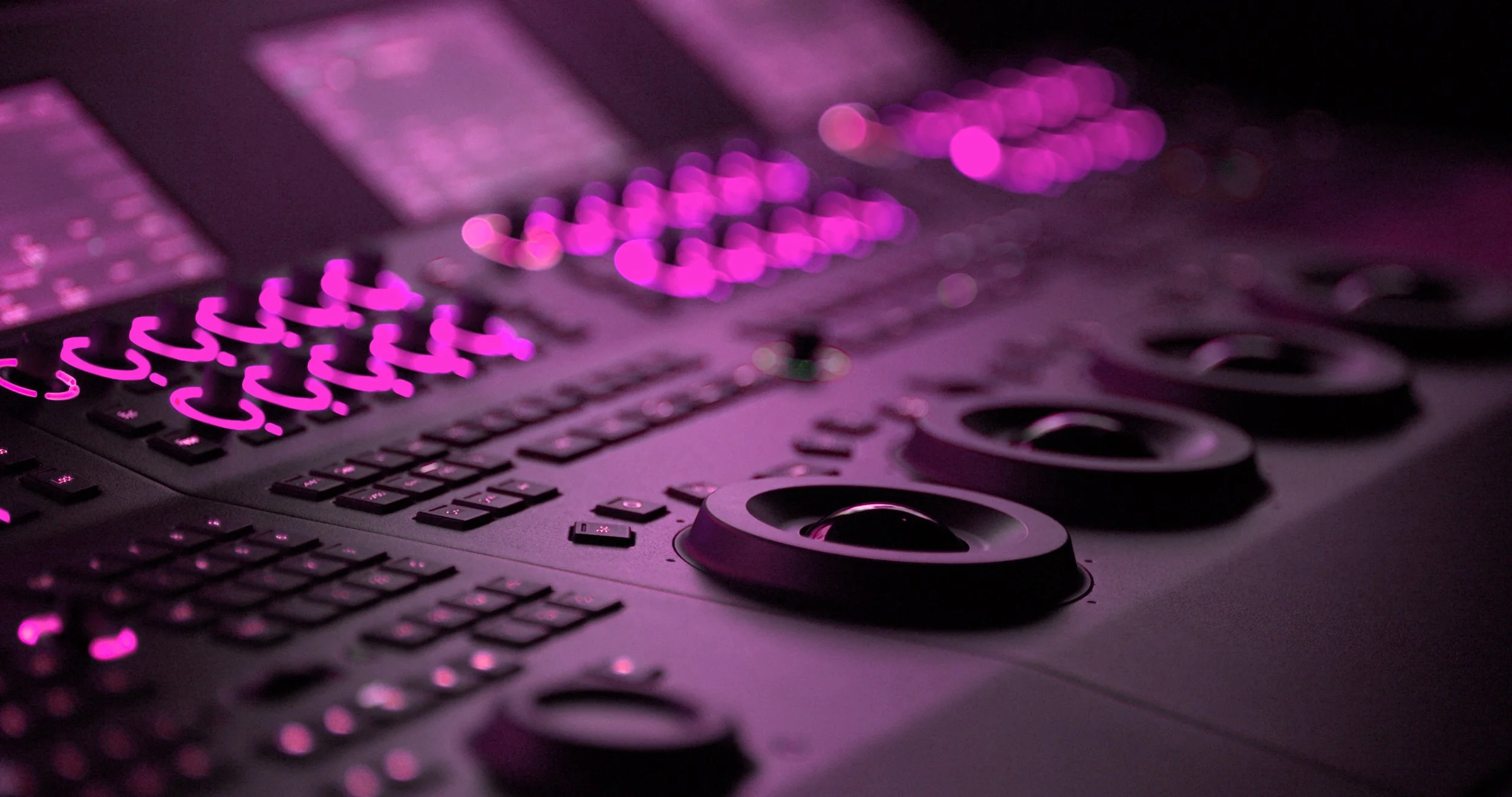 Close-up of a laptop keyboard with illuminated pink backlit keys, and a touchpad with circular controls, set against a dark background.