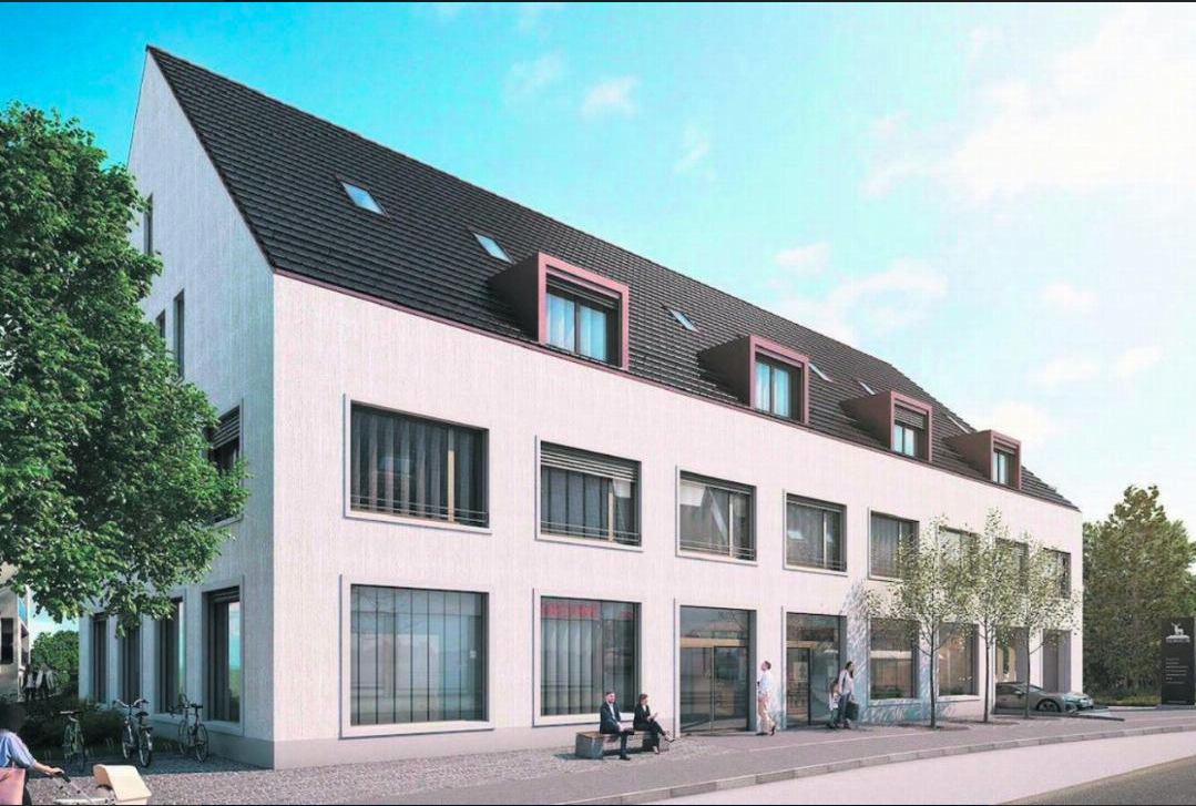 Ein modernes viergeschossiges Gebäude mit großer Fensterfront und einem Satteldach. Es gibt einige Menschen, die vor dem Gebäude stehen oder sitzen, und Fahrräder, die in der Nähe abgestellt sind.