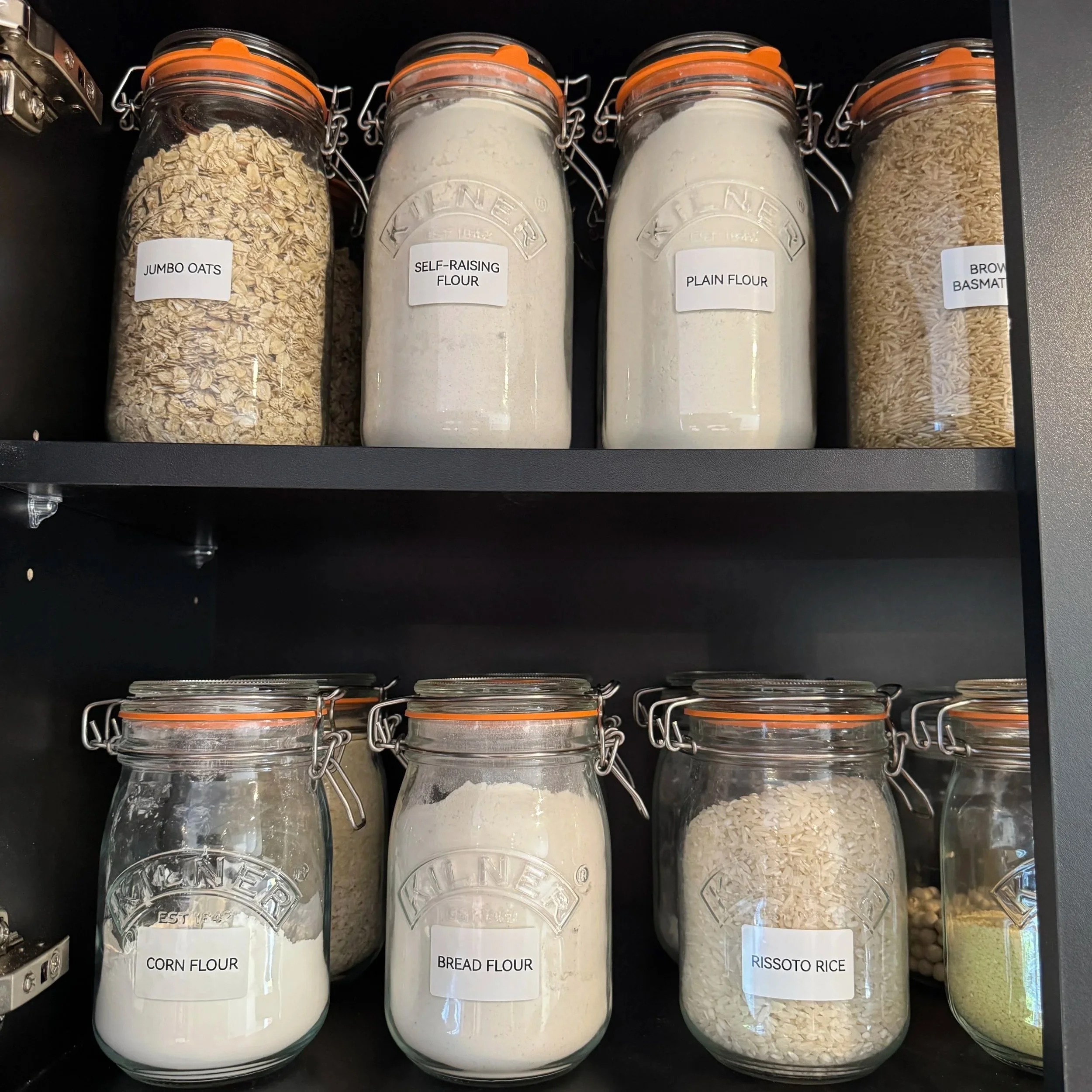 Organised pantry shelf with labelled food storage jars