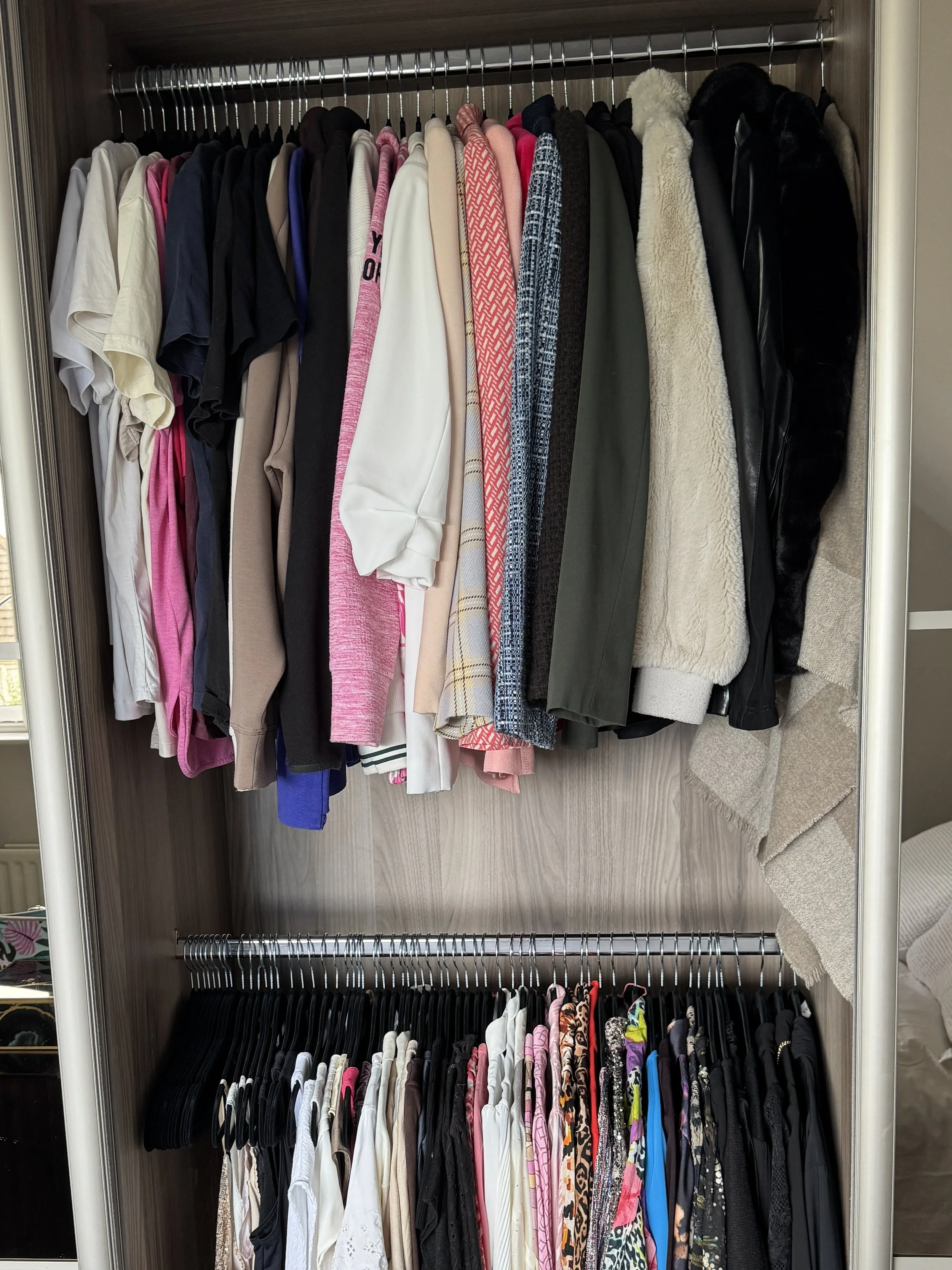 Organised wardrobe with clothing grouped by type and length, using matching hangers to create a practical, easy-to-maintain wardrobe system.