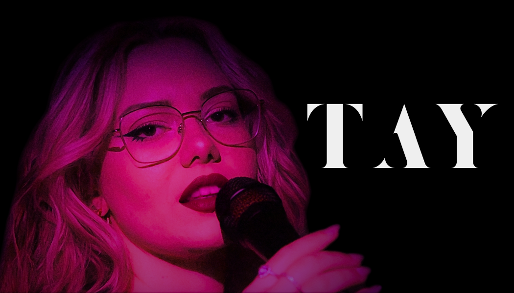 TAY performing live with a microphone, party entertainment in Wales on a black background with 'TAY' written in bold white letters