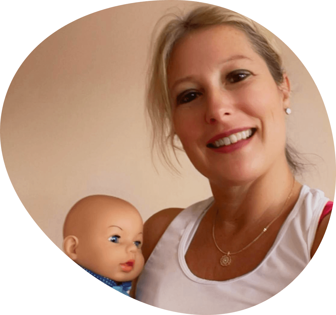 Eine Frau hält ein Baby und lächelt in die Kamera.