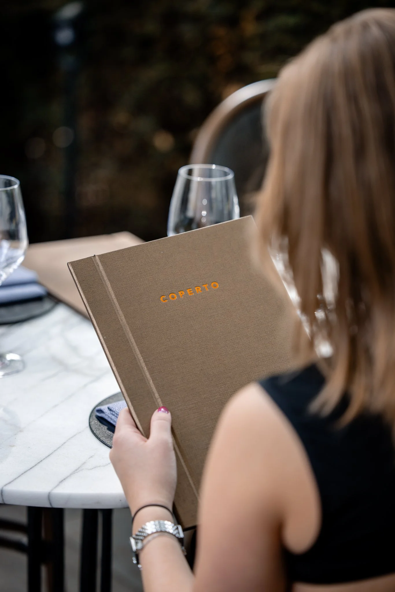 Een vrouw met een horloge en een armband leest een menu 
