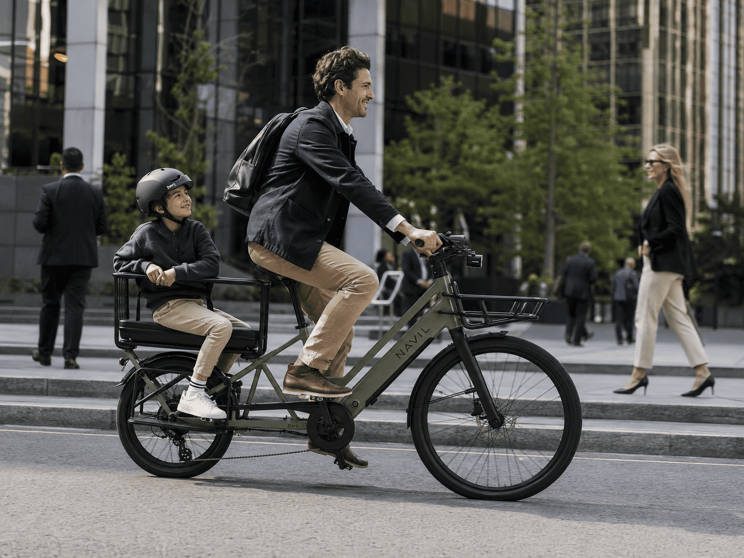Un homme et un enfant en vélo électrique dans une ville moderne, avec des bâtiments en verre en arrière-plan, les deux portant un casque et souriant.