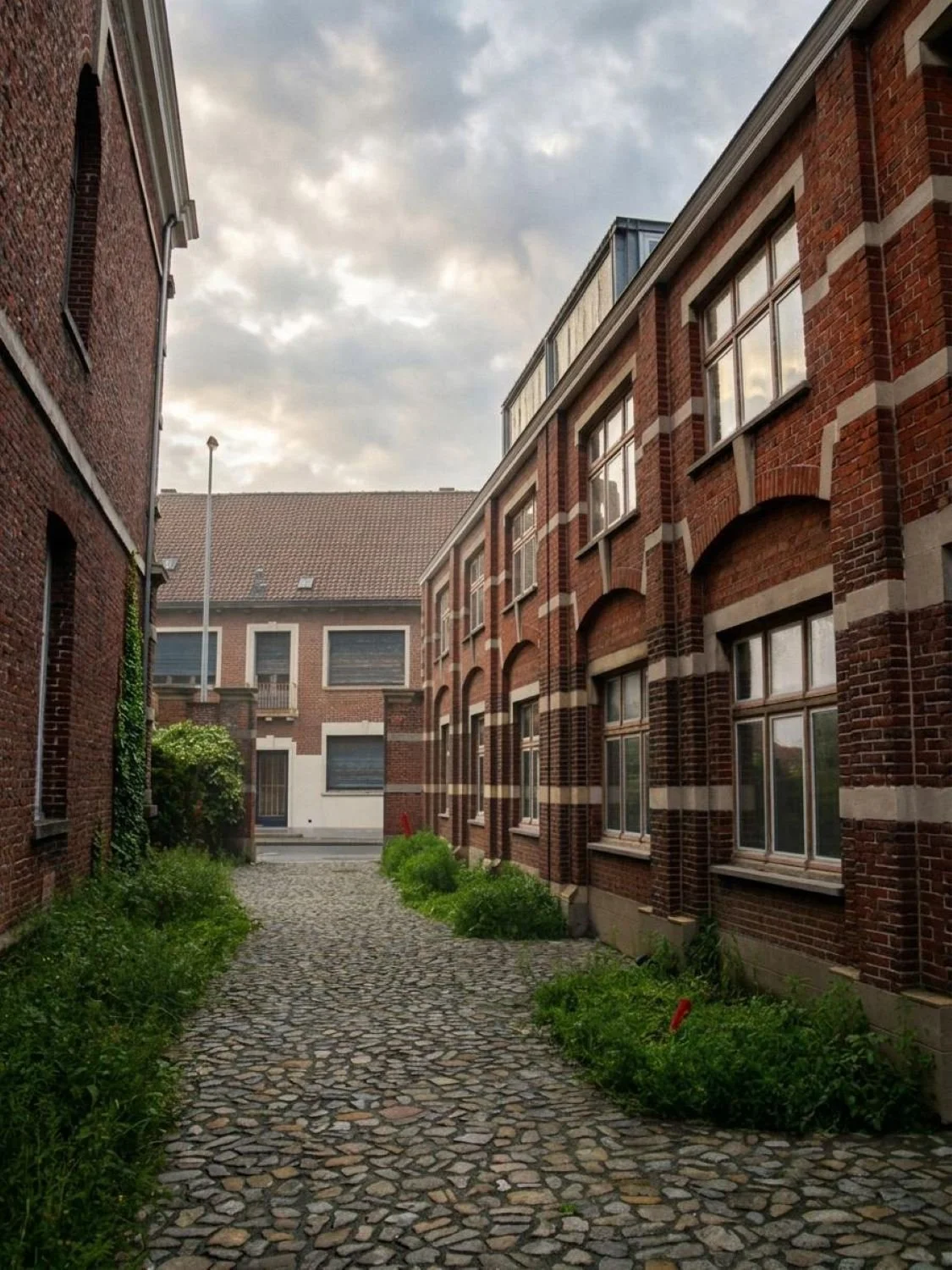 Minimalist warehouse conversion in Flanders, Belgium, transforming a historic industrial building into contemporary office space through adaptive re-use