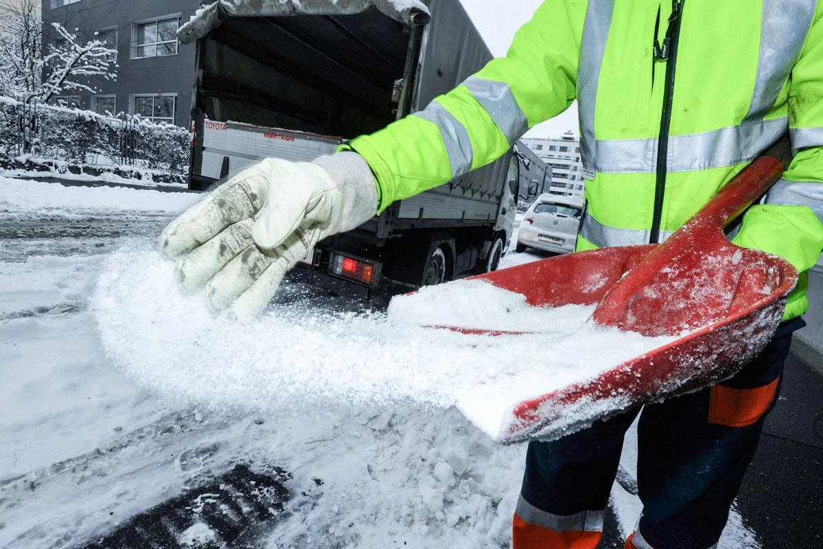 Hier kümmert sich ein Hausmeister um den Winterdienst. Er beseitigt Schnee und streut die Straße.