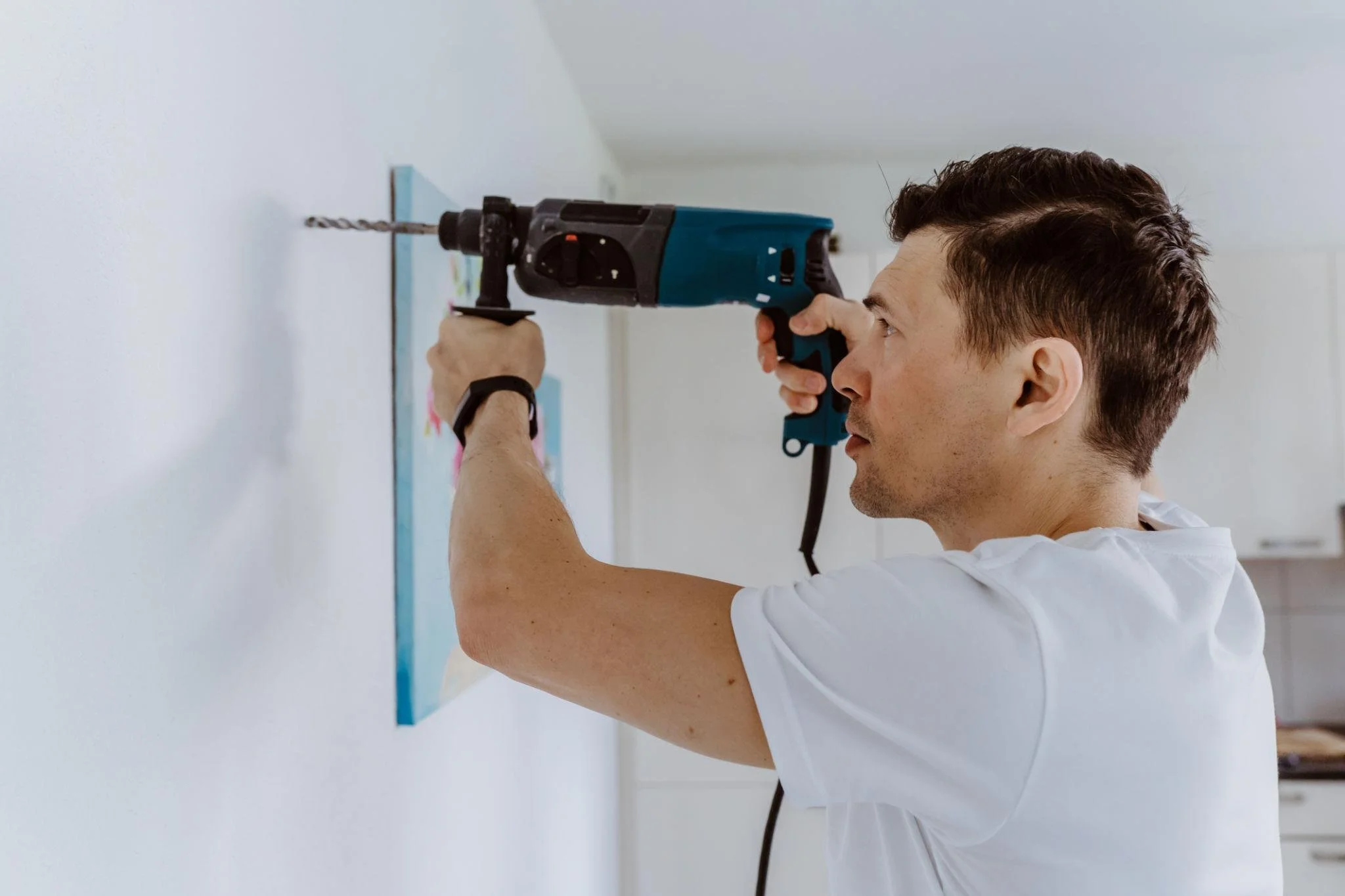 Hier arbeitet ein Hausmeister und bohrt ein Loch in die Wand.