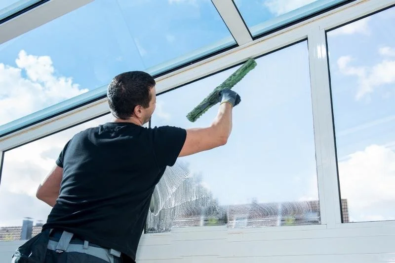 Hier sieht man einen Mitarbeiter, der ein Fenster putzt.