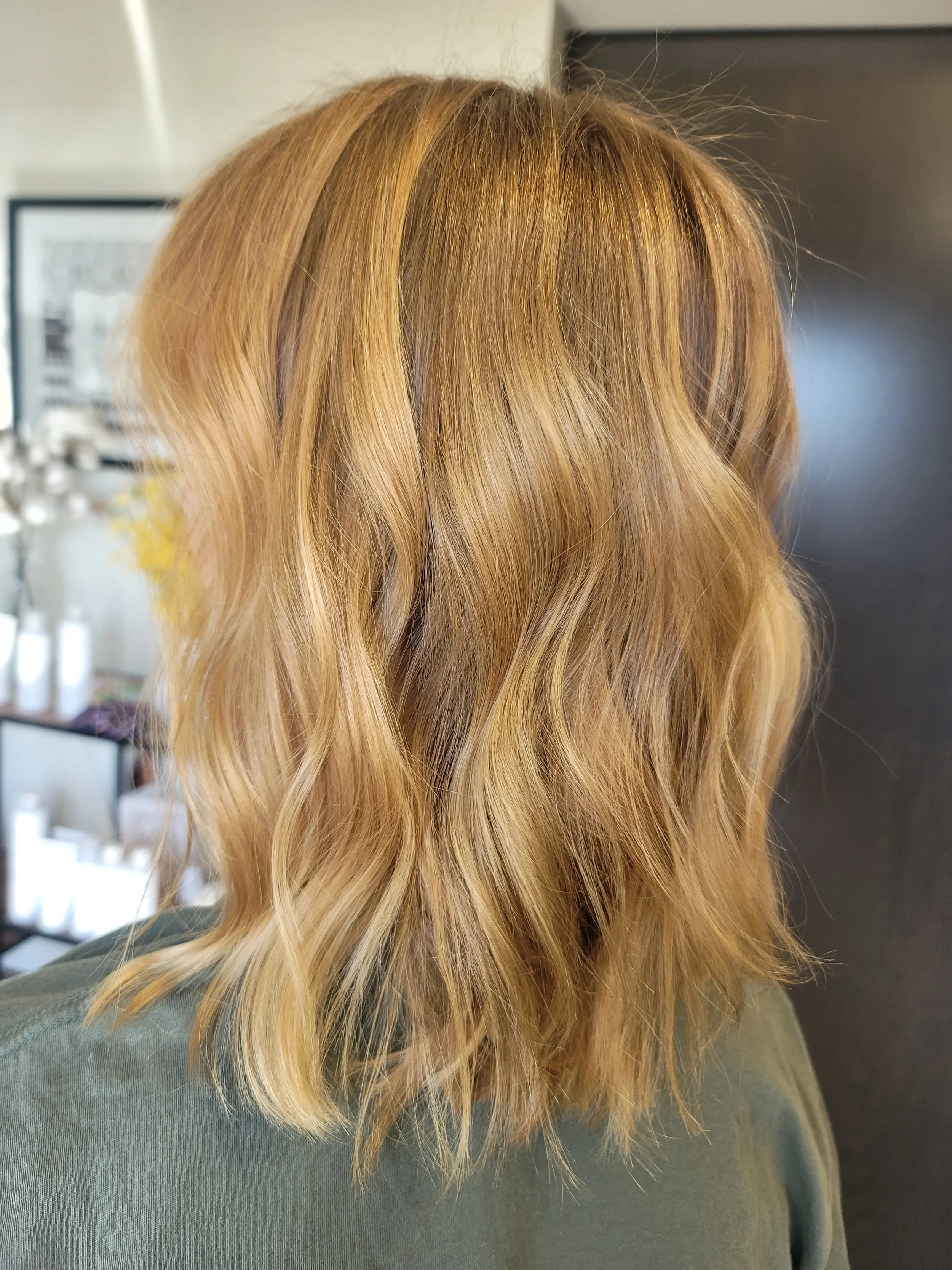 A person with wavy, blonde hair seen from behind.