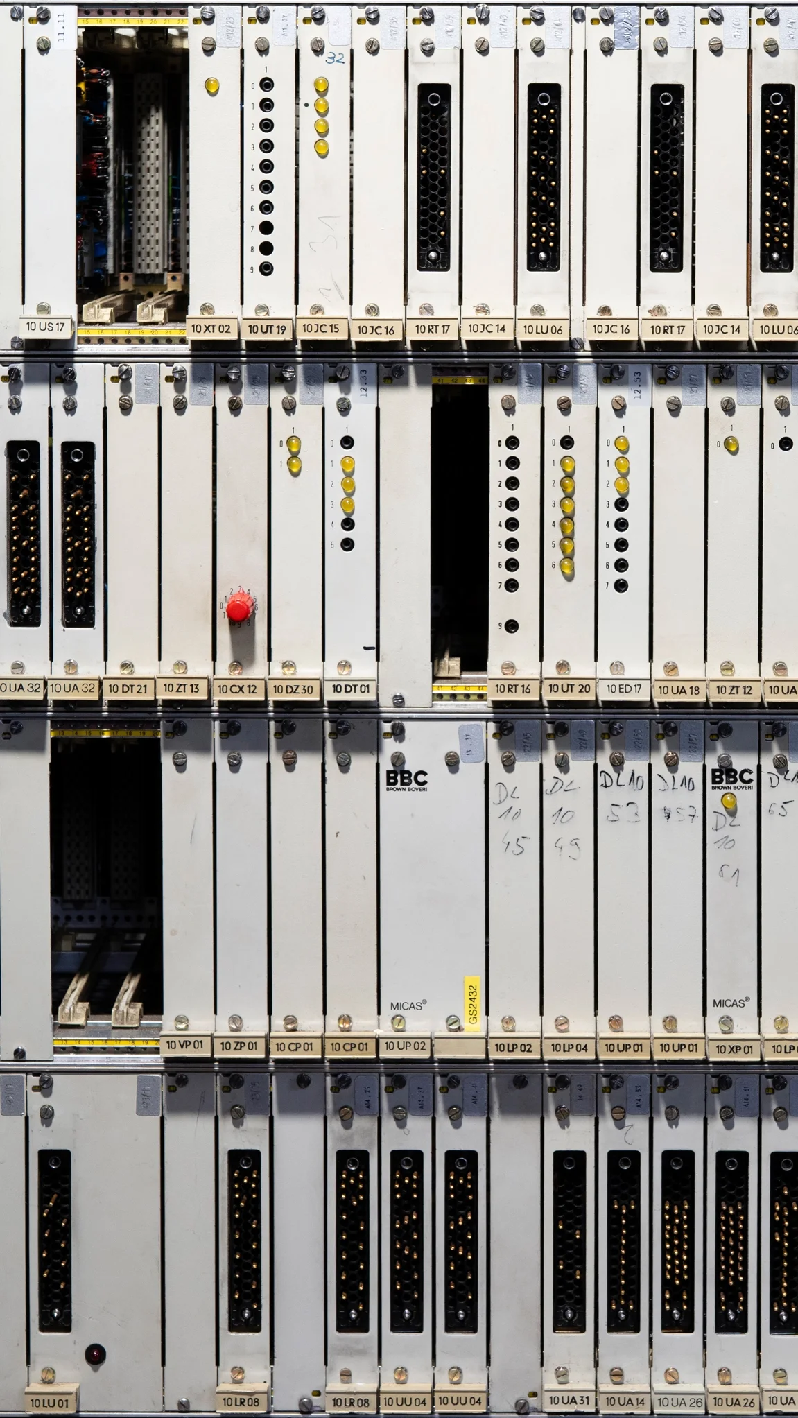 Elektronische Steuerungssysteme mit weißen Modulen, vielen schwarzen Steckern, gelben Leuchtdioden und some handgeschriebenen Notizen.