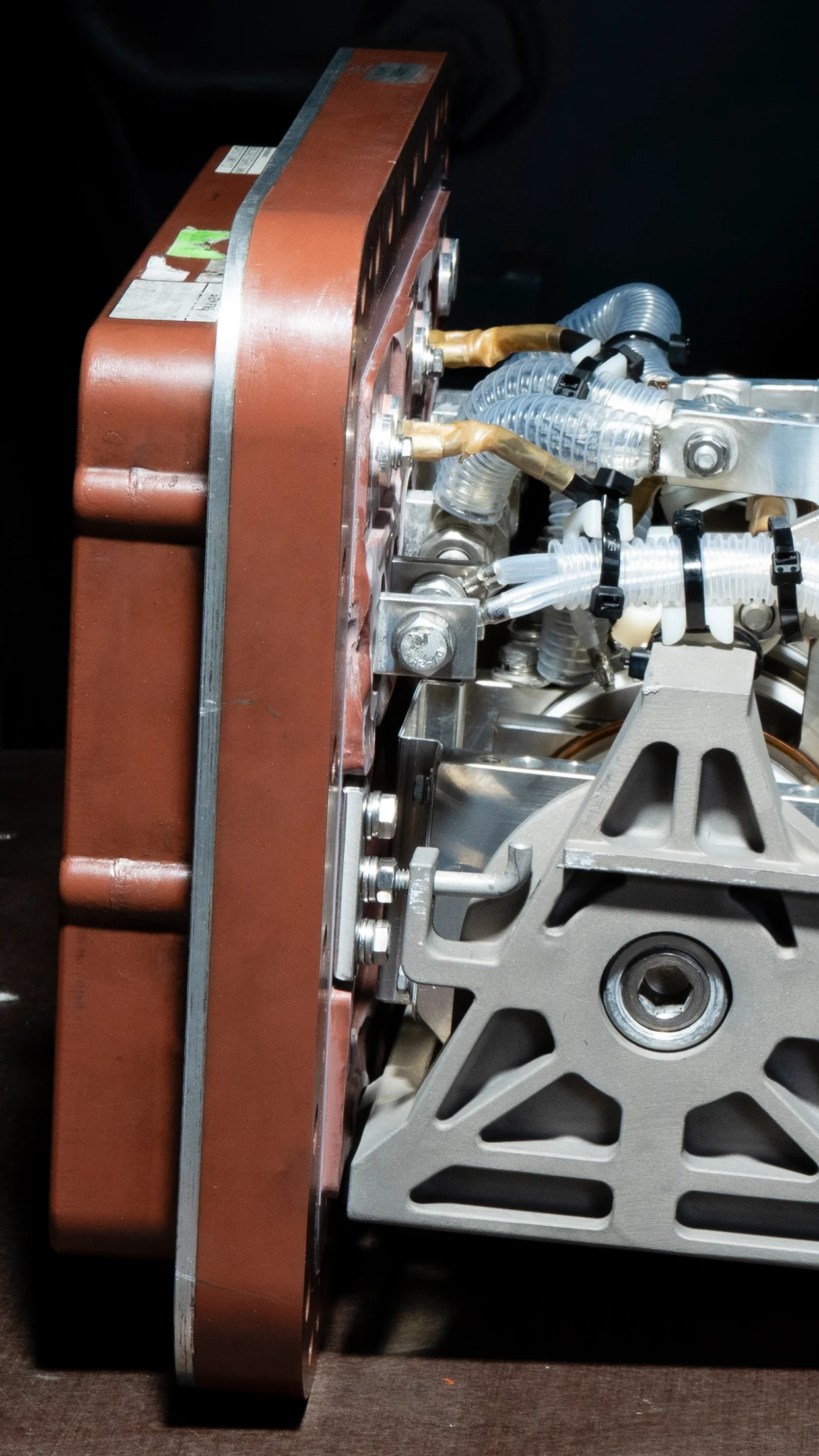 Ein komplexes mechanisches Bauteil mit unterschiedlichen Rohren, Schrauben und Metallteilen, wahrscheinlich Teil eines technischen oder wissenschaftlichen Geräts.