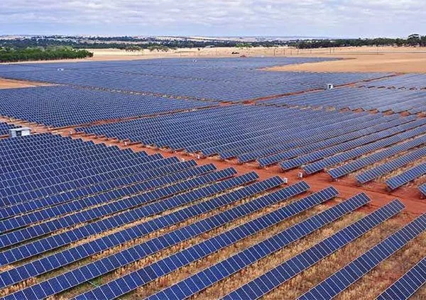 A large solar farm with rows of solar panels installed on the ground in an open field.