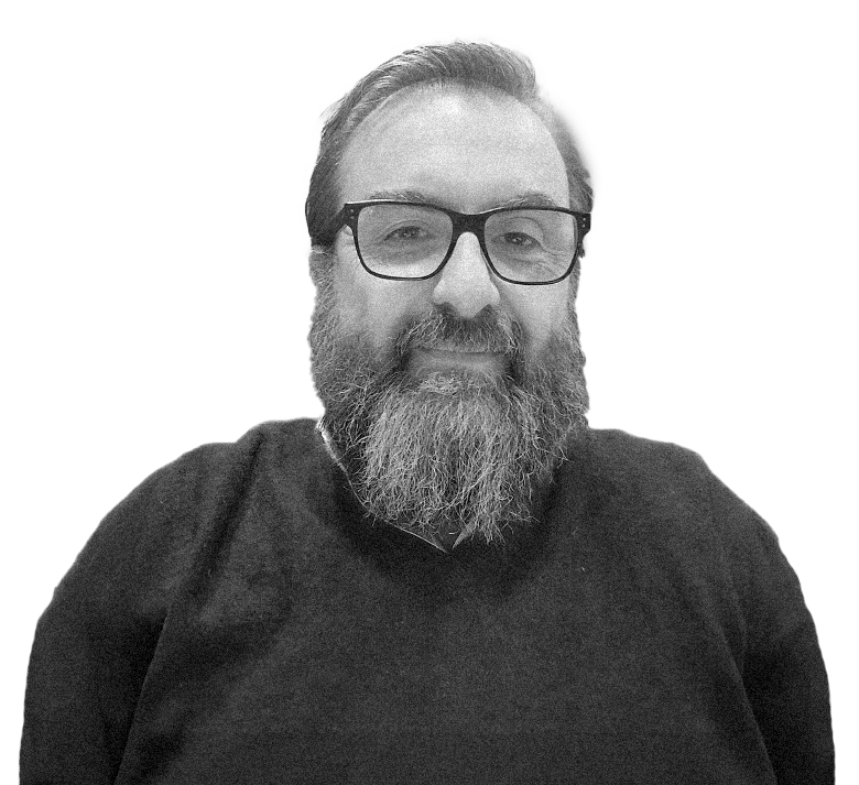 Uomo con barba e occhiali, sorridente, indossa un maglione scuro.