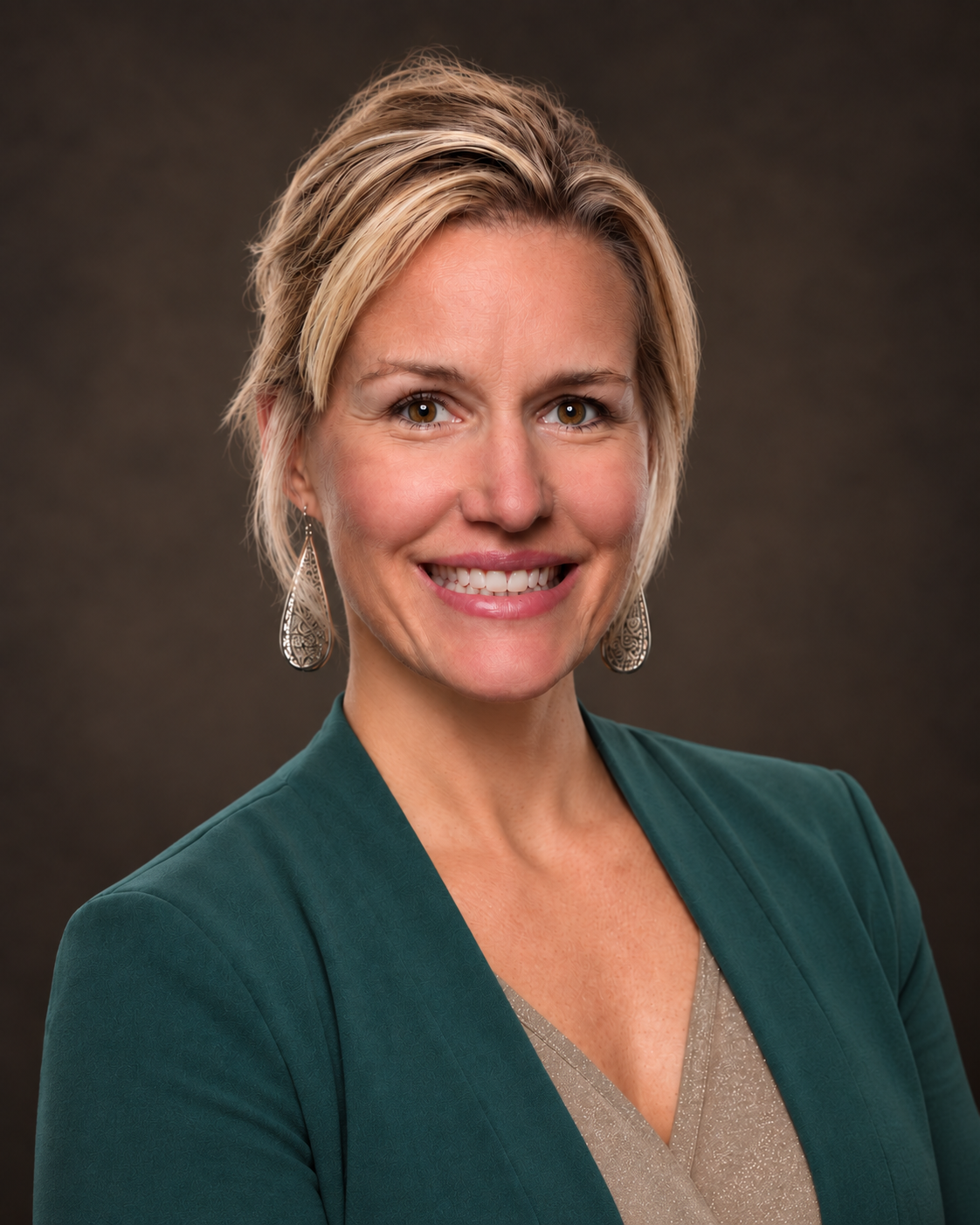Professional studio headshot of a woman in a teal blazer against a dark neutral background.
