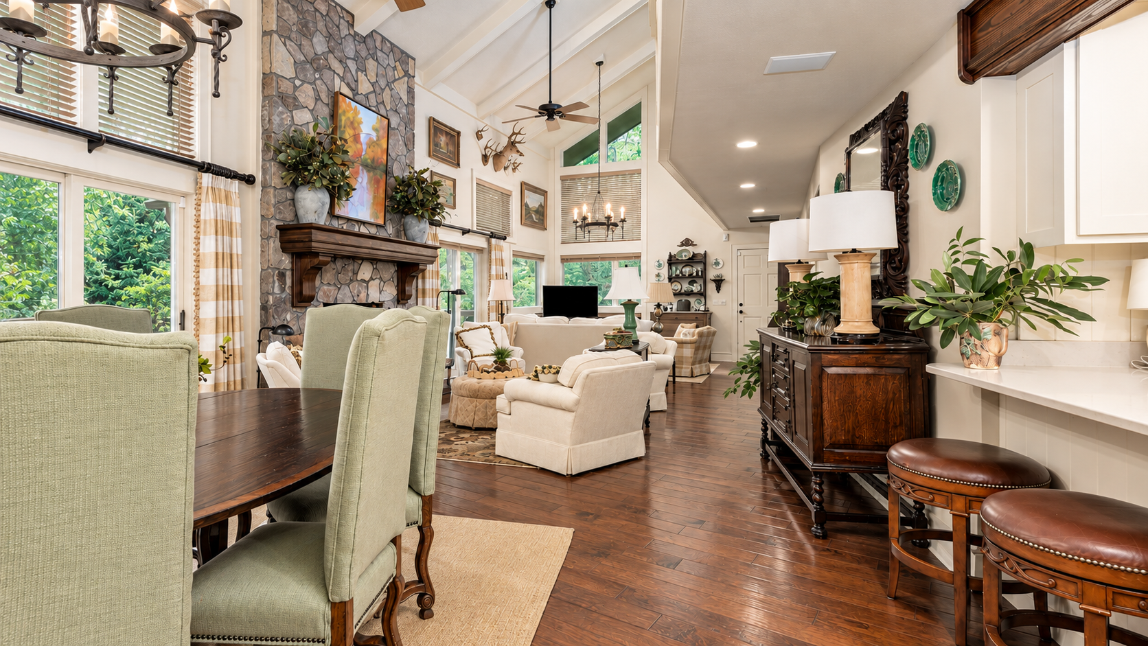 Bright open-plan living and dining room with vaulted ceiling, stone fireplace and hardwood floors.