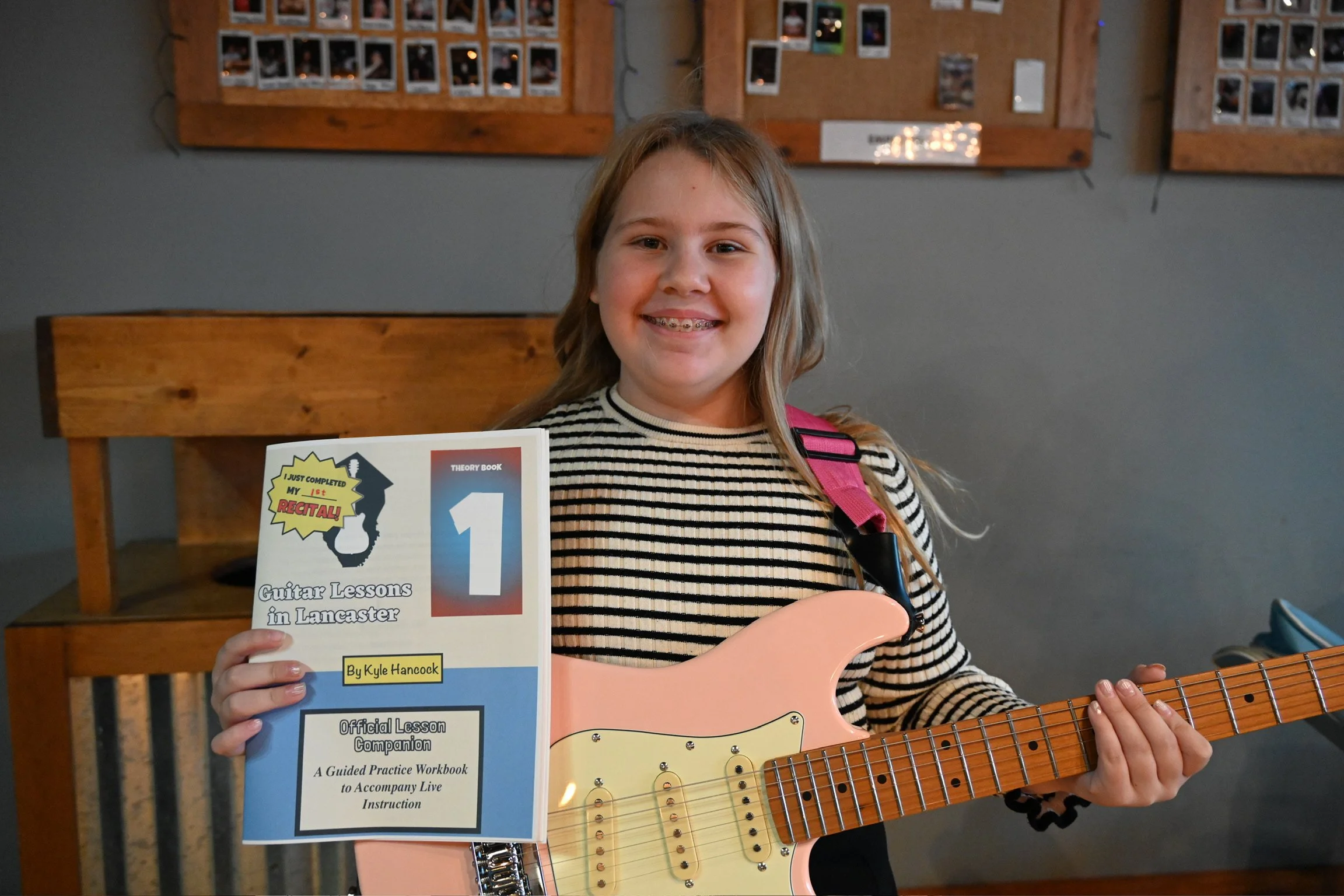Smiling girl with her electric guitar holding her Lesson Companion Book 1