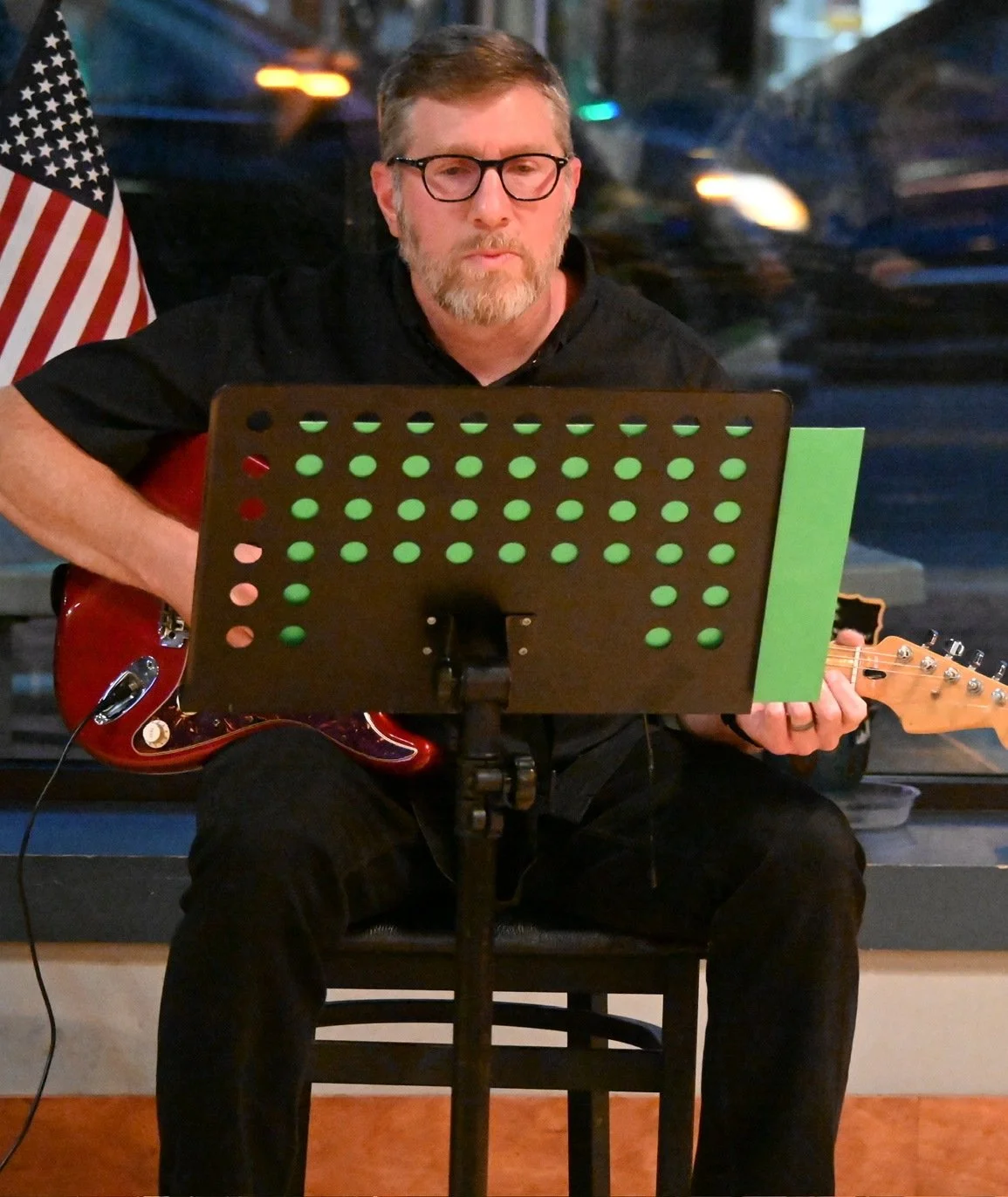 Adult guitar student playing a red electric guitar at a student recital