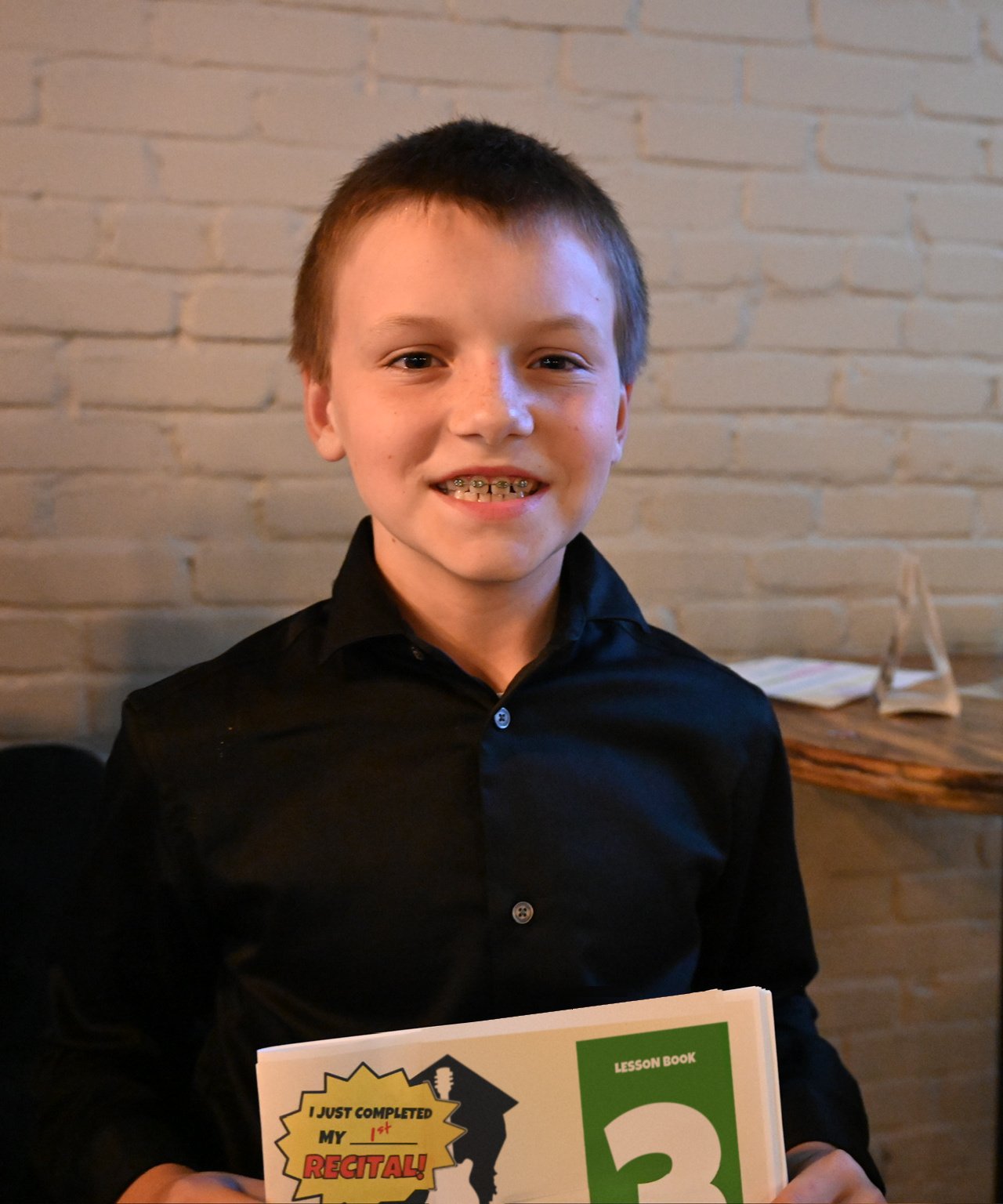 Smiling young guitar student holding his Lesson Companion Book 3