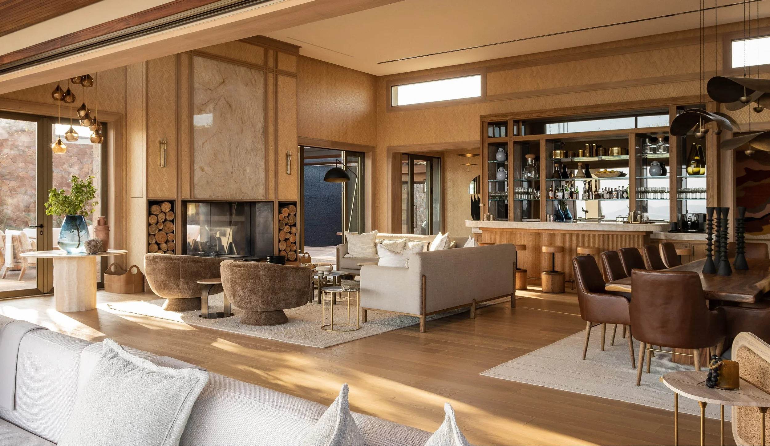 A spacious living room with modern decor, featuring a fireplace, wooden furniture, and large windows.