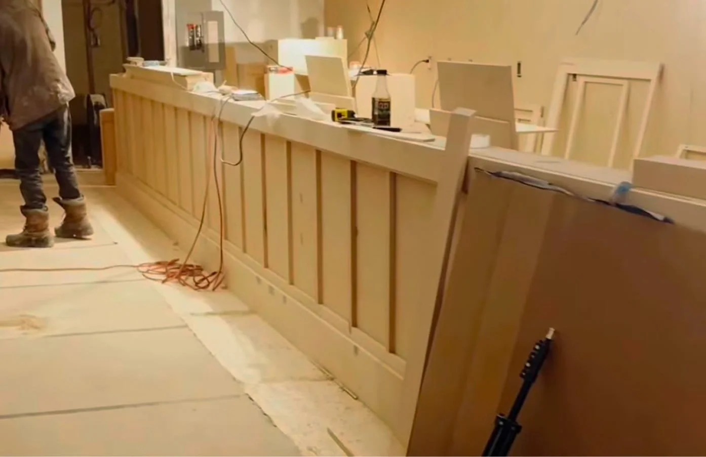 Interior of a room under construction with wooden cabinetry and tools on the counter.