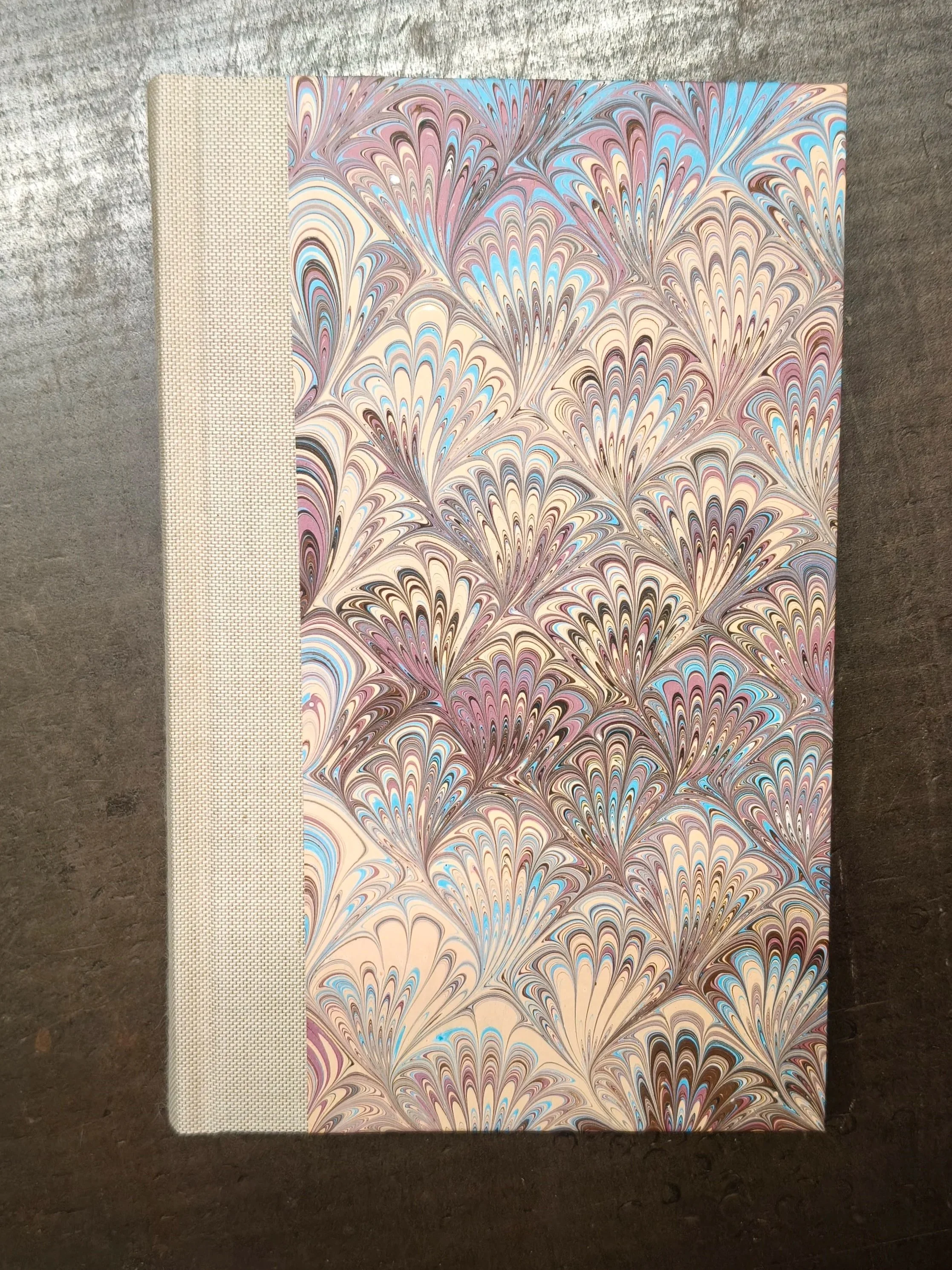 Copertina del libro 'Cirano di Bergerac' di Edmond Rostand restaurato, pubblicato nel 1900, con dorso in tela grezza e copertina in carta fiorentina colorata.