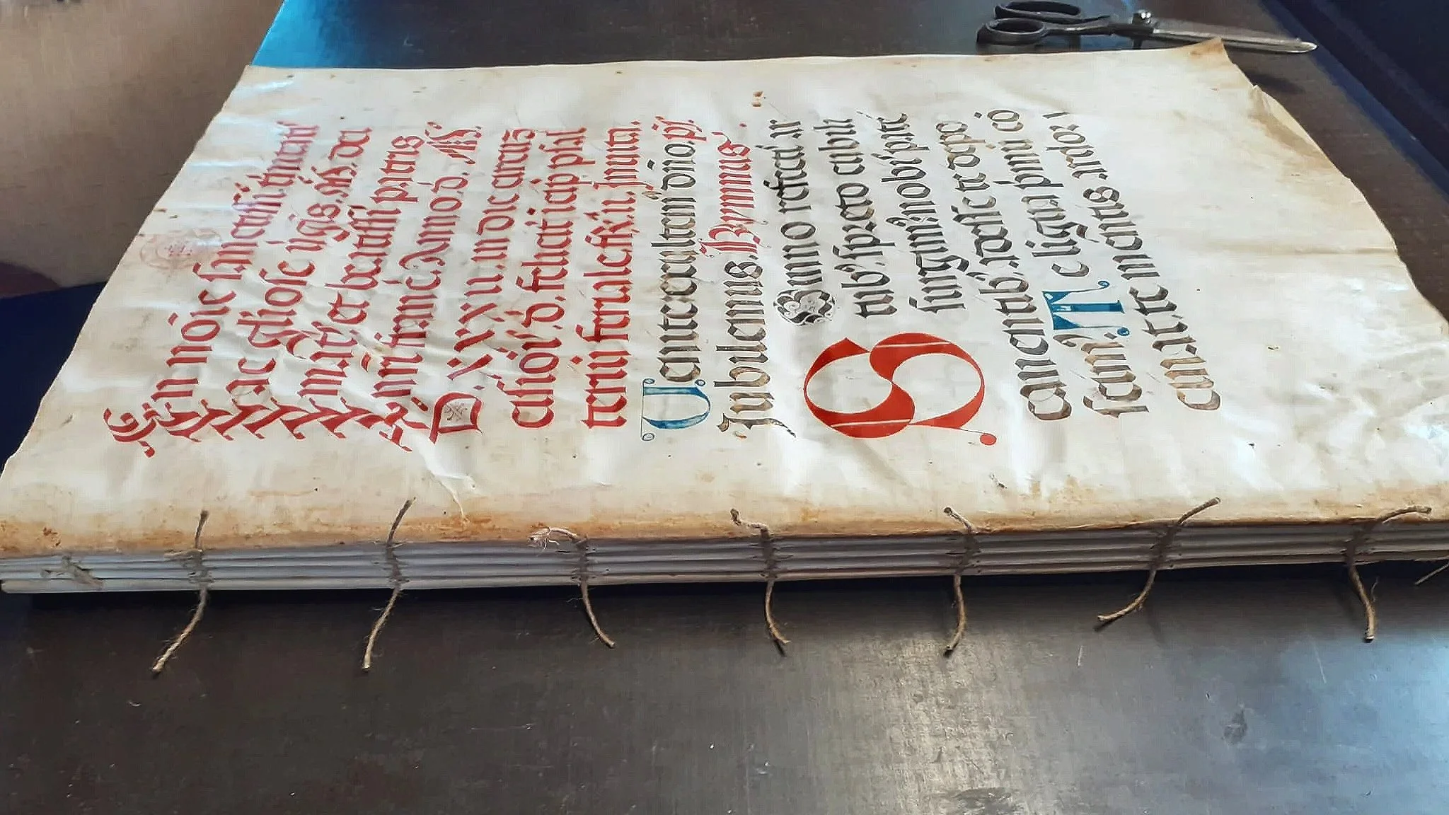 agina di un manoscritto del 1400 medievale con testo in lettere gotiche e dorso scoperto rilegato con spago prima del restauro.
