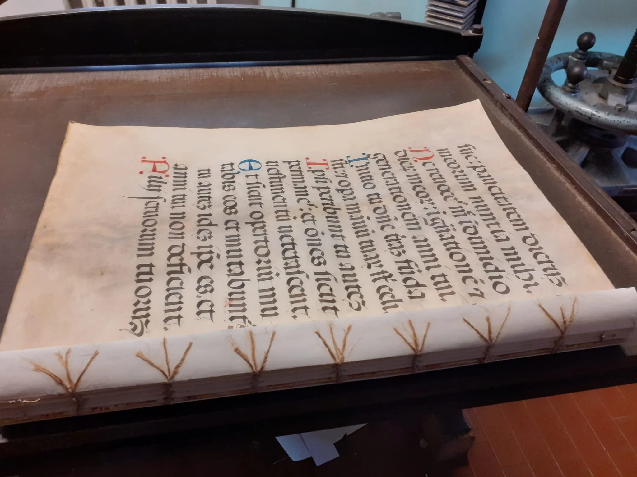 Pagina di un manoscritto del 1400 medievale con testo in lettere gotiche, alcune parti in rosso e altre in nero, decorazioni e iniziali elaborate, dopo il restauro.
