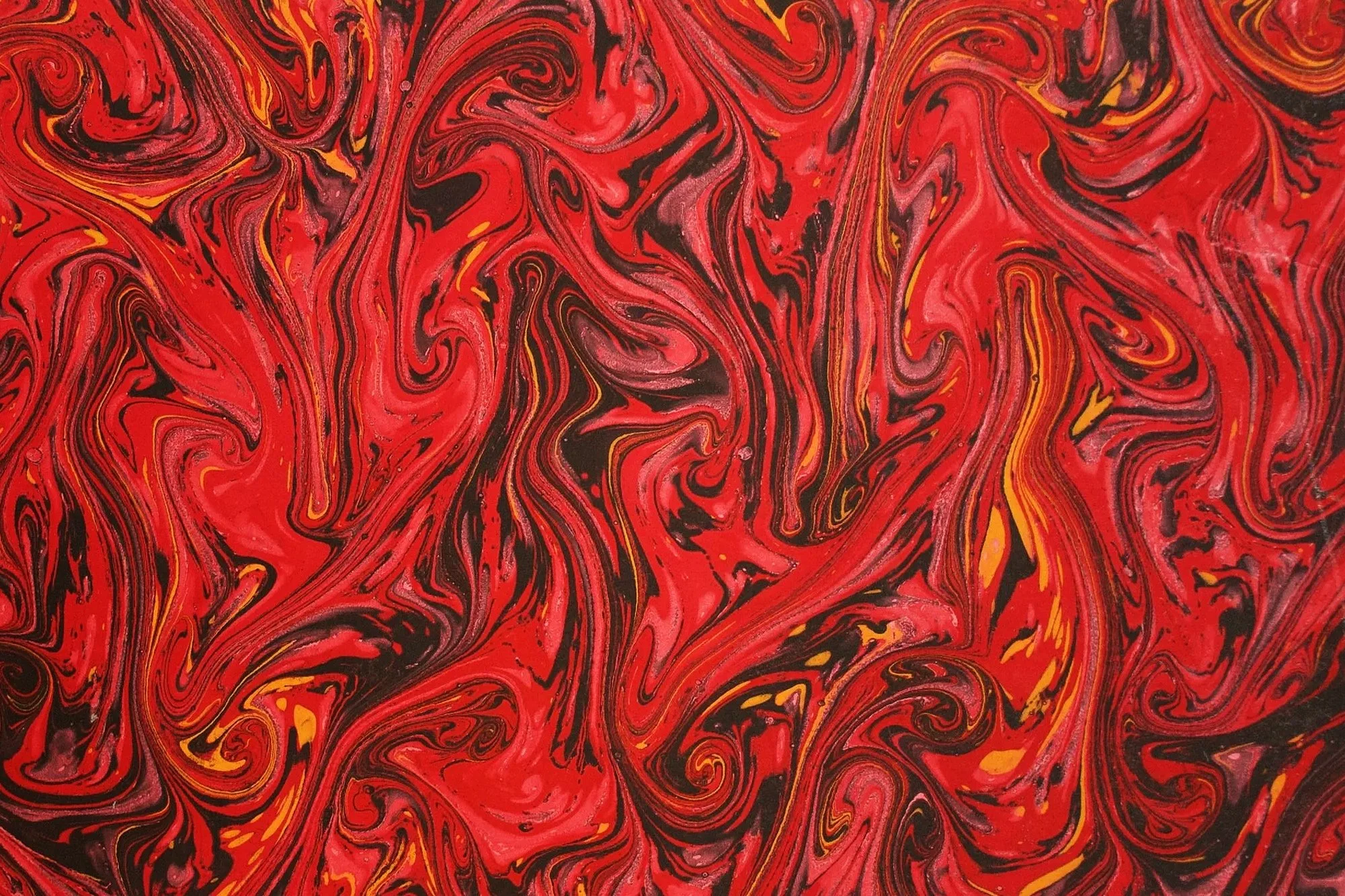 Foto di un foglio di carta fiorentina rossa, caratterizzato da venature irregolari nei toni del nero e del dorato, con una superficie decorativa dall'effetto marmorizzato