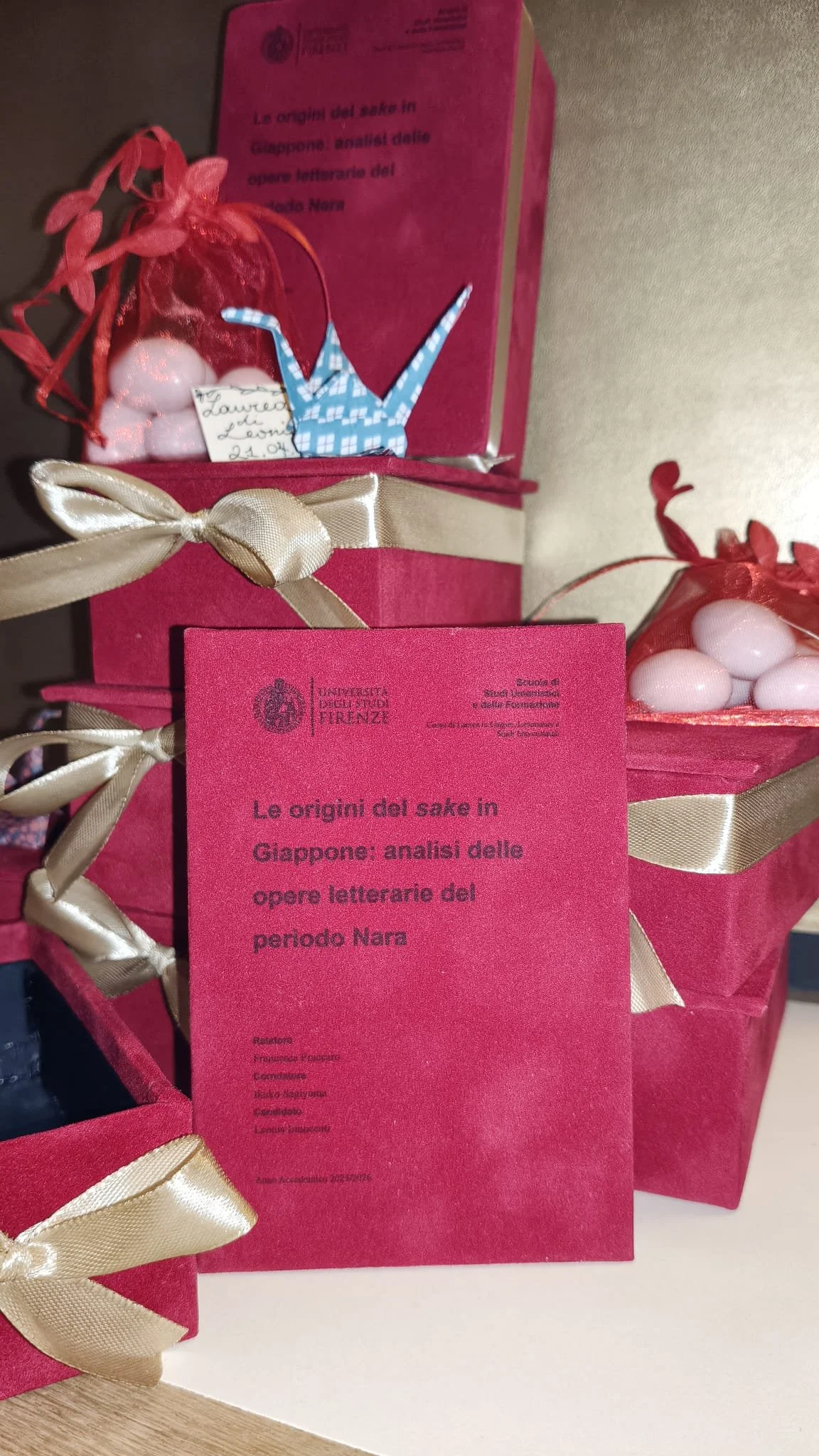 Set 10 bomboniere in velluto rosso e stampa a inchiostro nero, decorate con fiocco dorato, confetti, origami e bigliettino su sfondo dorato.