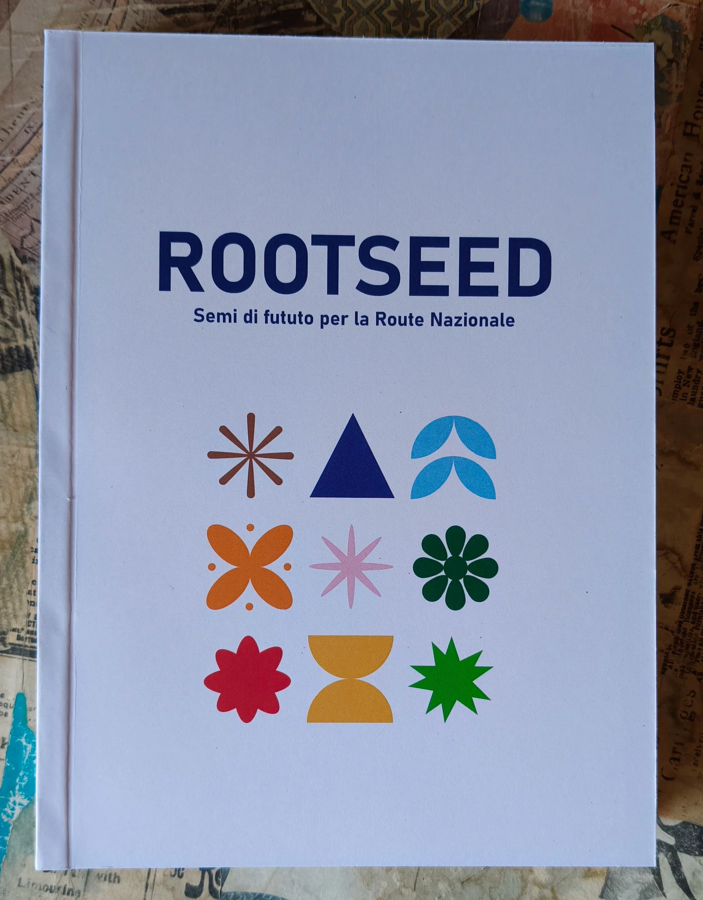 Libro brossurato “Rootseed” con copertina bianca e stampa grafica a colori, realizzato con rilegatura artigianale.