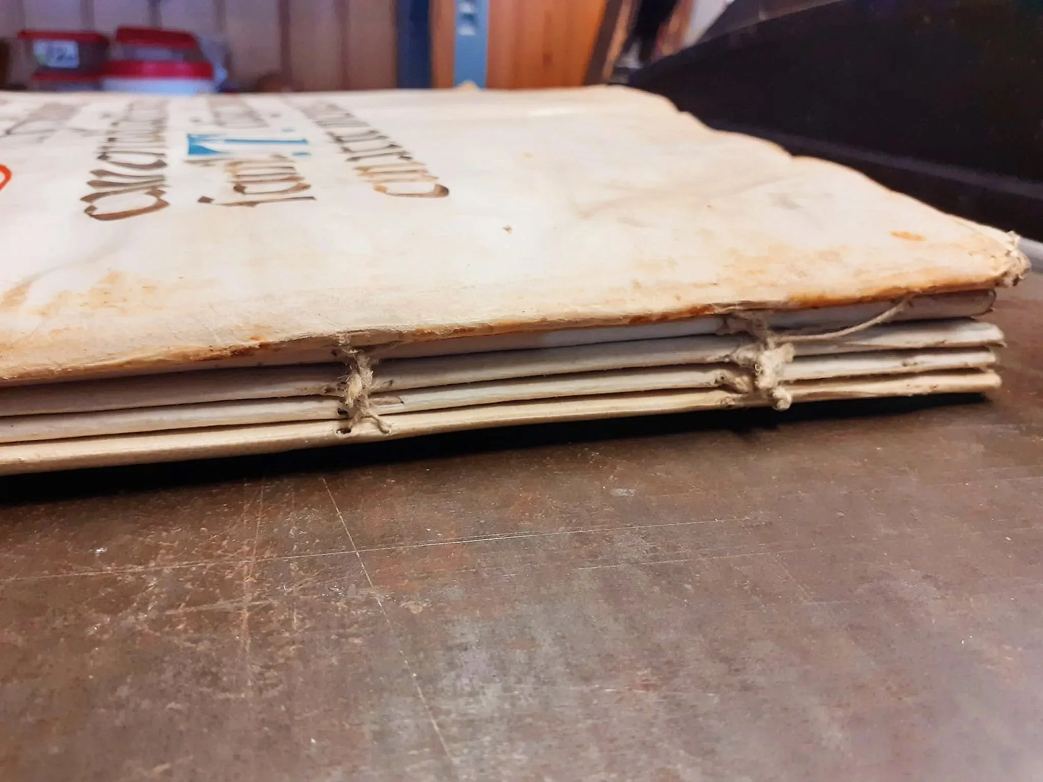 Pagina di un manoscritto del 1400 medievale con testo in lettere gotiche e dorso scoperto rilegato con spago durante il restauro.