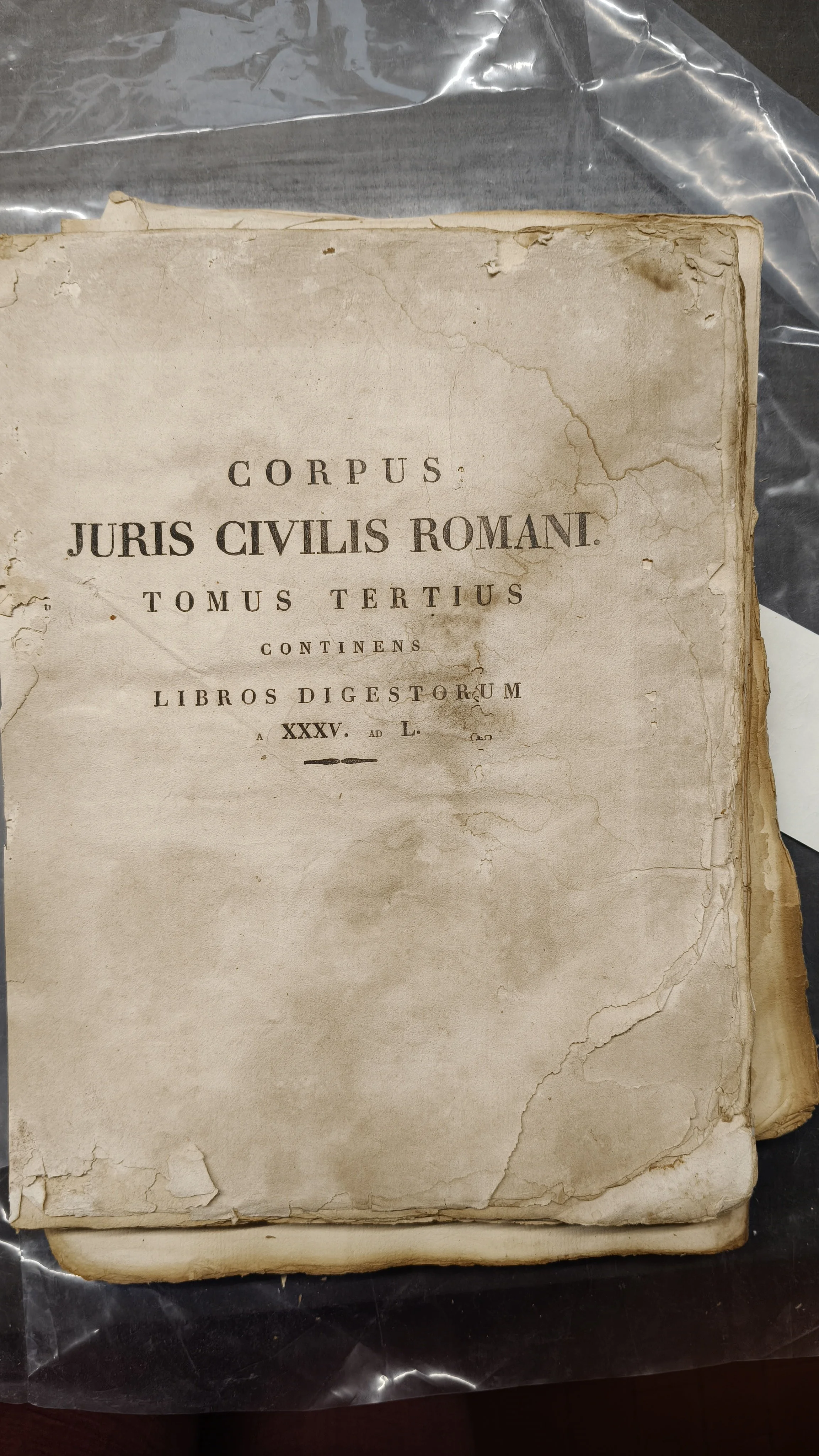 Una vecchia domanda di diritto romano, con angoli ammaccati e pagine ingiallite, intitolata 'Corpus Juris Civilis Romani'.