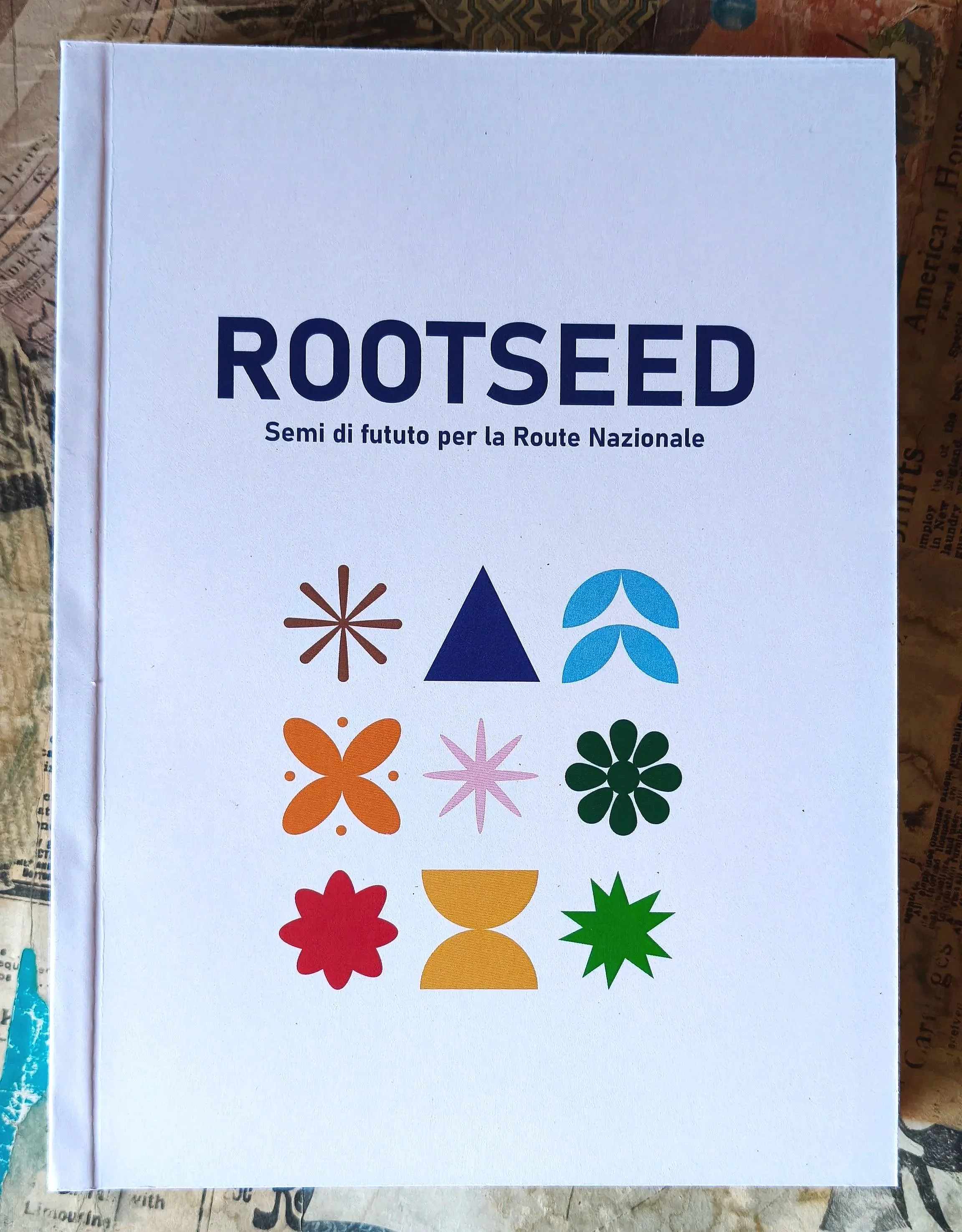 Libro brossurato “Rootseed” con copertina bianca e stampa grafica a colori, realizzato con rilegatura artigianale.