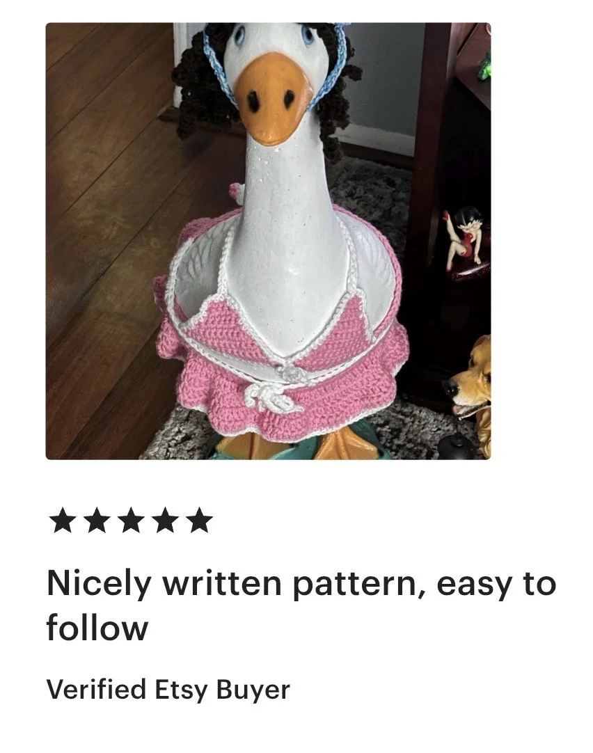 A decorative pink and white crocheted skirt on a goose-shaped statue.