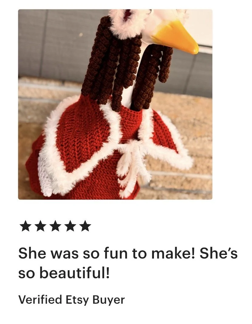 A handmade sock puppet resembling a decorated bird or turkey with brown yarn hair, yellow beak, and a red and white fluffy cloth body.