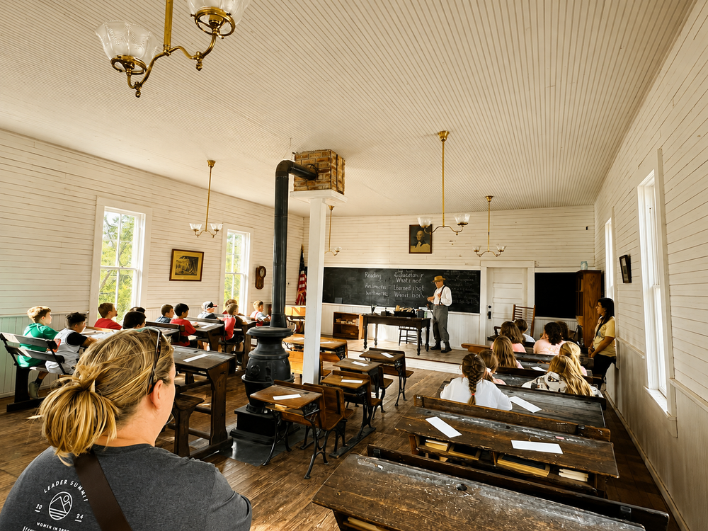 Visitors in a historic schoolroom at Harn Homestead