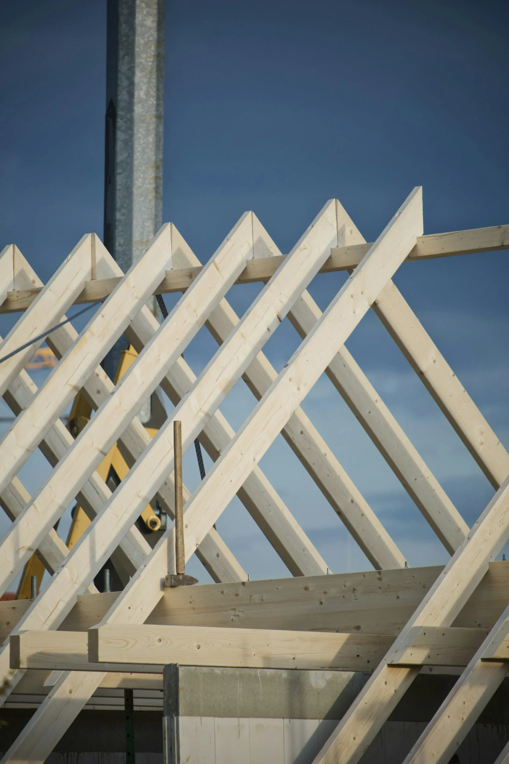 Construction site with wooden framing and a metal pole against a cloudy sky.