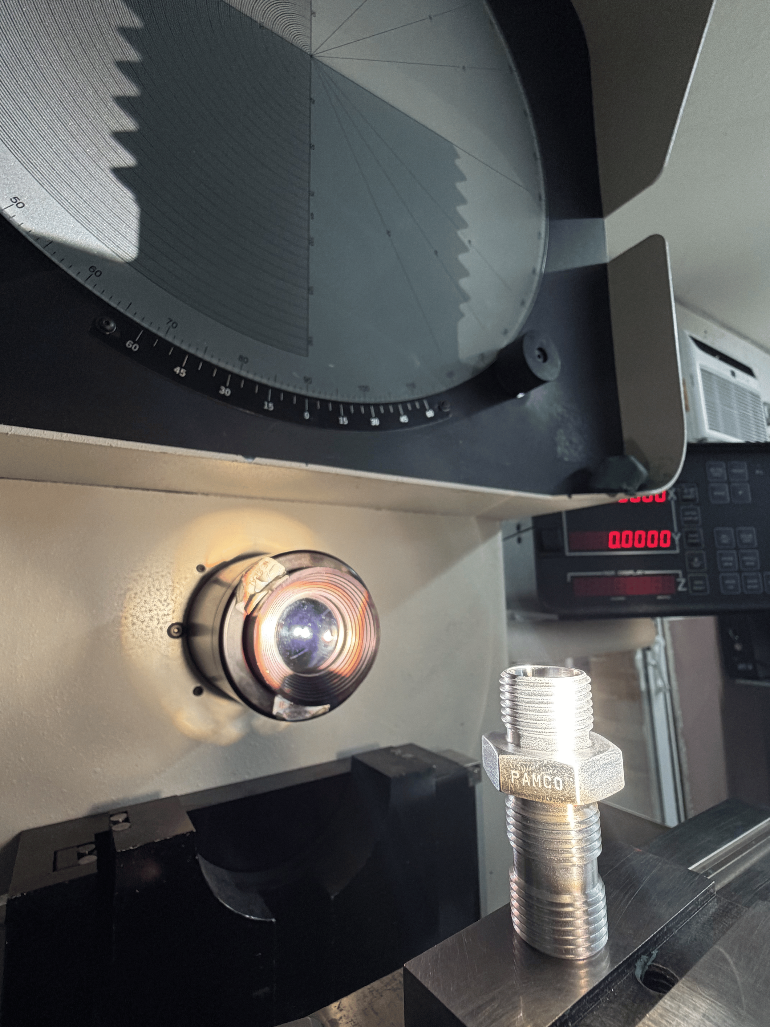 A laboratory setup with a metal cylindrical object placed on a platform, connected to a system with a large circular device with a shadowed interior and an outer rim, likely indicating a scientific or industrial experiment.