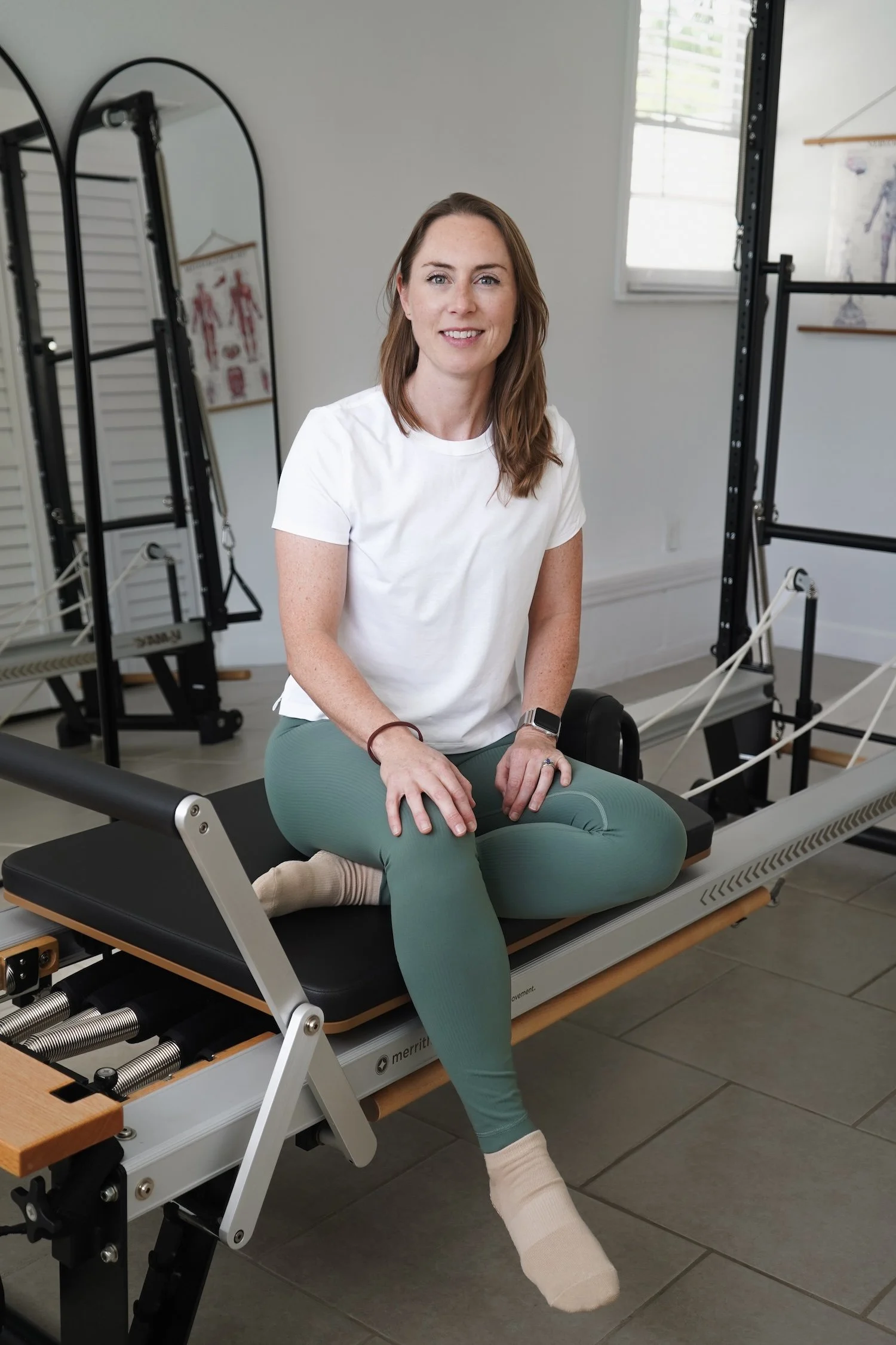 Picture of the owner, Pilates instructor Clare Allard. Woman wearing green pants in a studio.