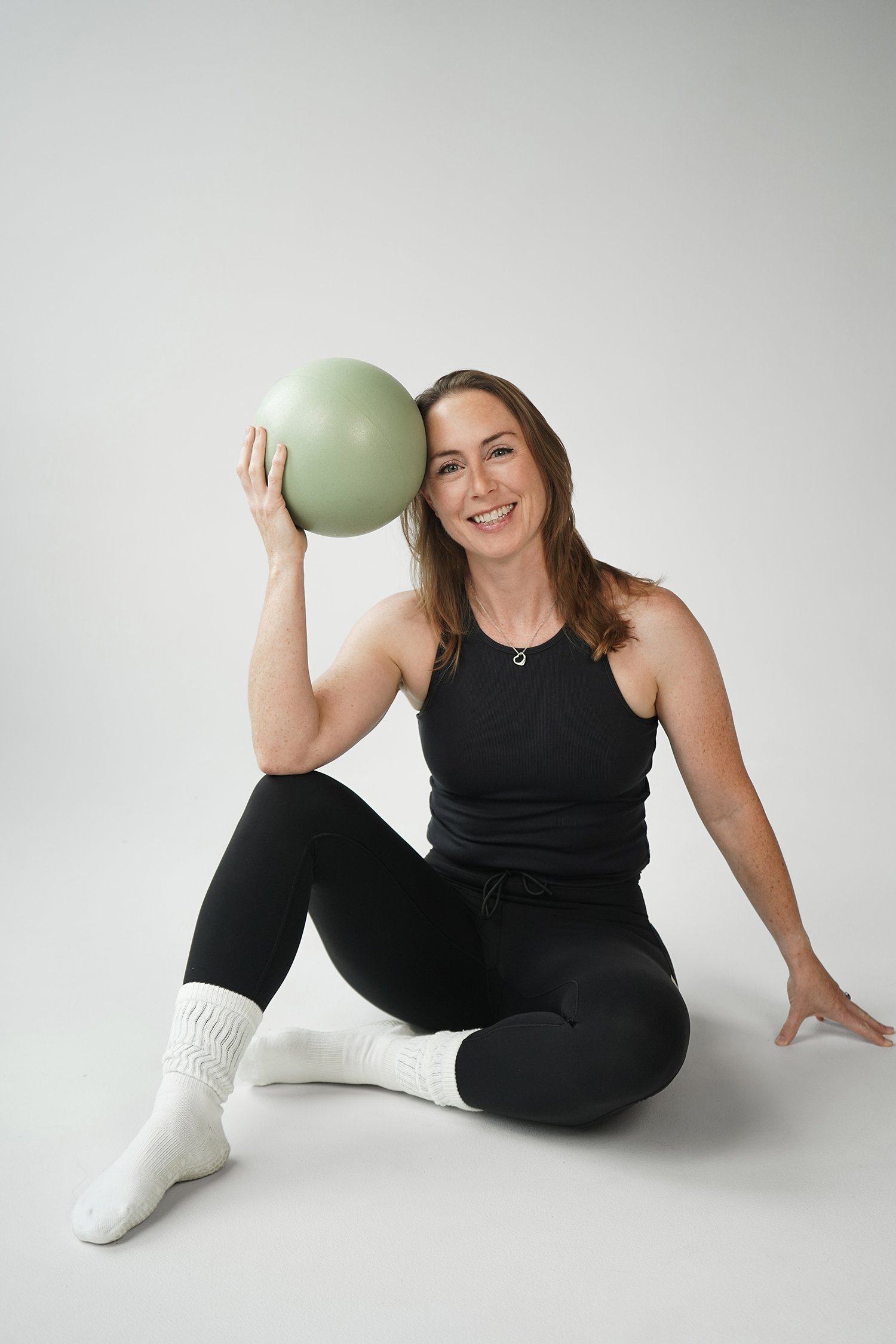 Clare posing with a ball in a pilates studio