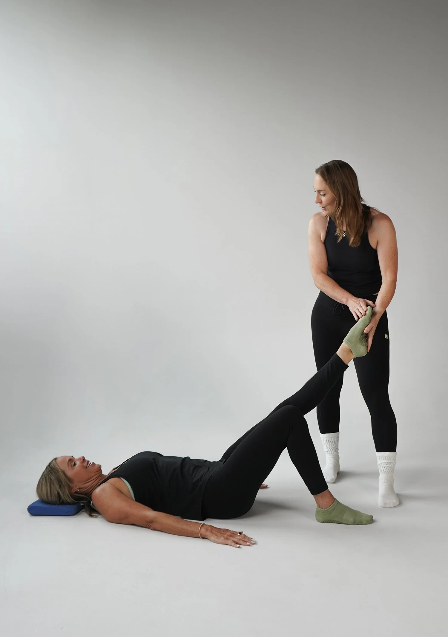 Pilates instructor teaching leg stretch in pilates studio