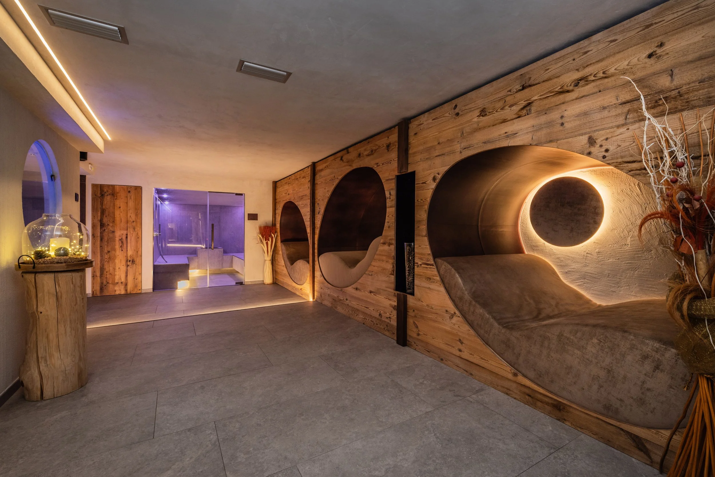 Interno di una stanza moderna con pareti in legno, arredi curati, illuminazione soffusa e decorazioni naturali.